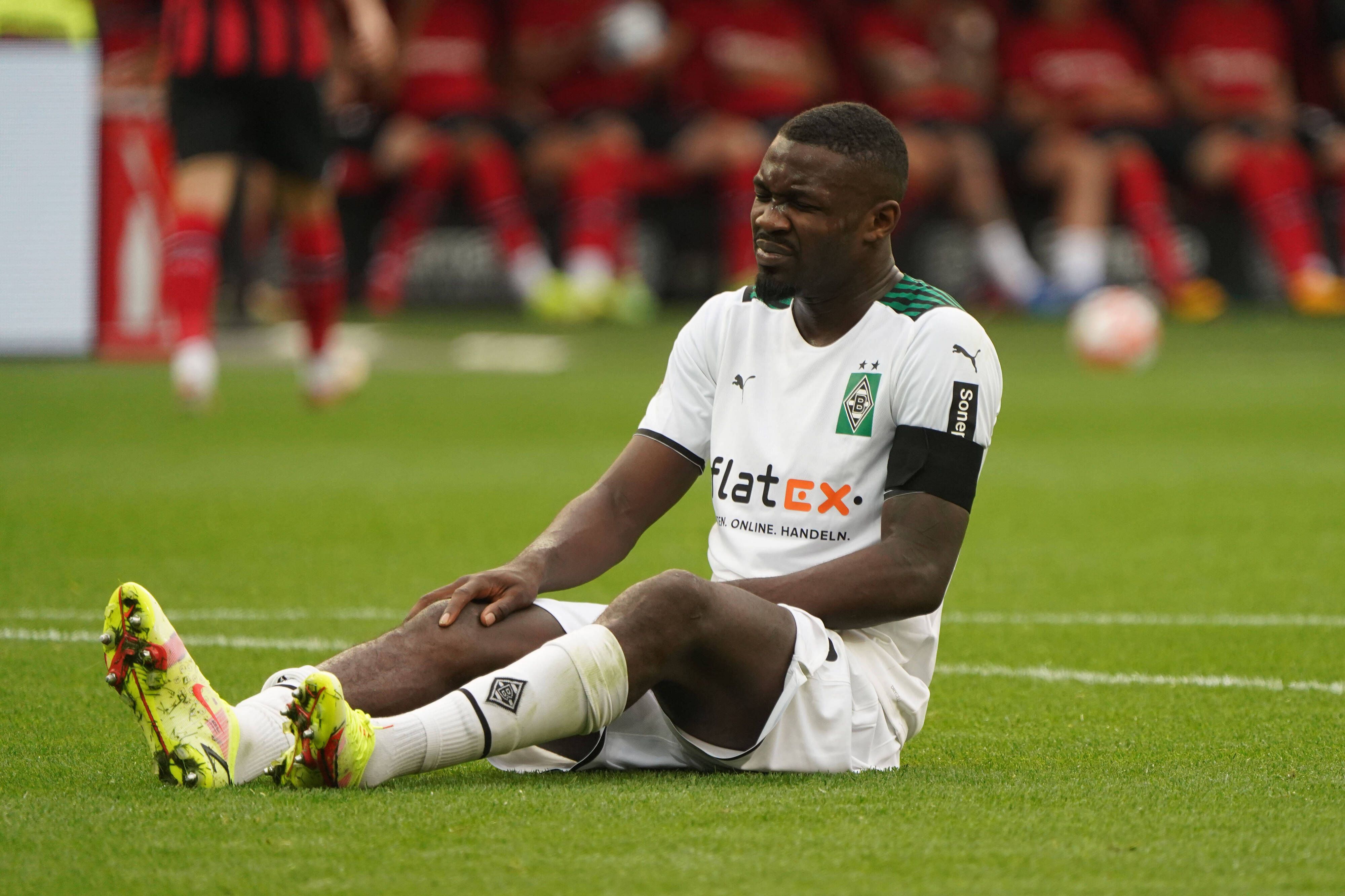 Marcus Thuram von Borussia Mönchengladbach sitzt im Spiel gegen Leverkusen am 21. August 2021 auf dem Boden und hält sich sein verletztes Knie.