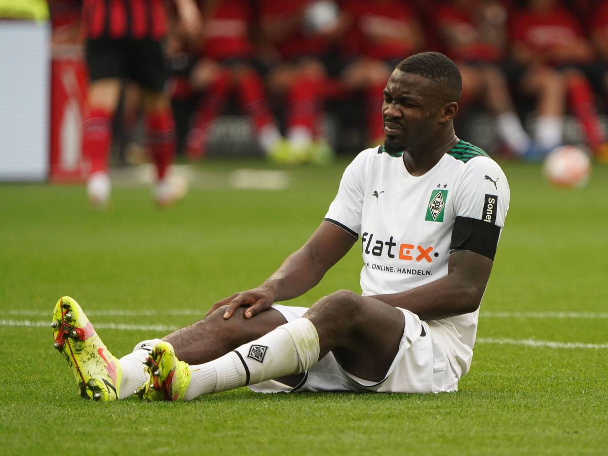 Marcus Thuram von Borussia Mönchengladbach sitzt im Spiel gegen Leverkusen am 21. August 2021 auf dem Boden und hält sich sein verletztes Knie.