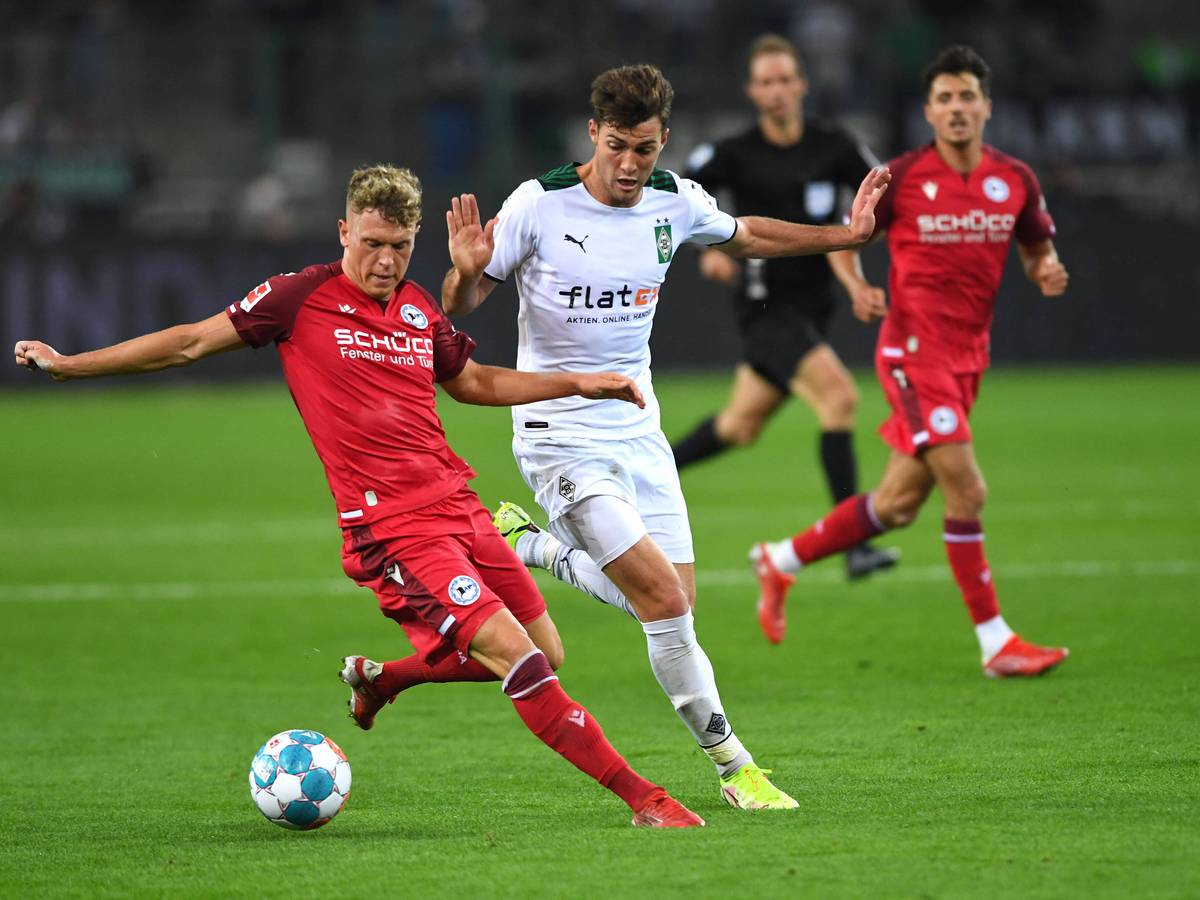Gladbach-Profi Joe Scally (M.) im Zweikampf mit Bielefelds Robin Hack (l.) beim Bundesliga-Duell zwischen der Borussia und der Arminia am 12. September 2021