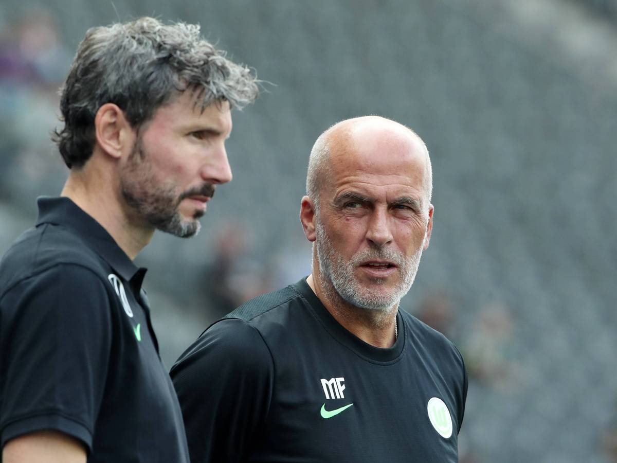 Ex-Gladbach-Trainer Michael Frontzeck (r.) arbeitet aktuell als Co-Trainer unter Mark van Bommel (l.) beim Fußball-Bundesligisten VfL Wolfsburg. Auf diesem Foto sind die beiden am 21. August 2021 im Berliner Olympiastadion zu sehen. Frontzeck blickt zu van Bommel rüber.