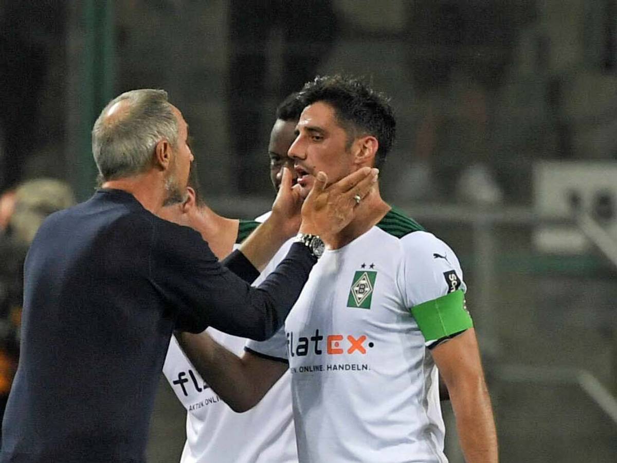 Gladbach-Coach Adi Hütter (l.), jüngst von den Profifußballern in Deutschland zum Trainer der vergangenen Saison gewählt worden, spricht am 12. September 2021 mit seinem Kapitän Lars Stindl, der Borussias Jahrtausend-Torschütze ist. Hütter fasst Stindl mit den Händen ins Gesicht.