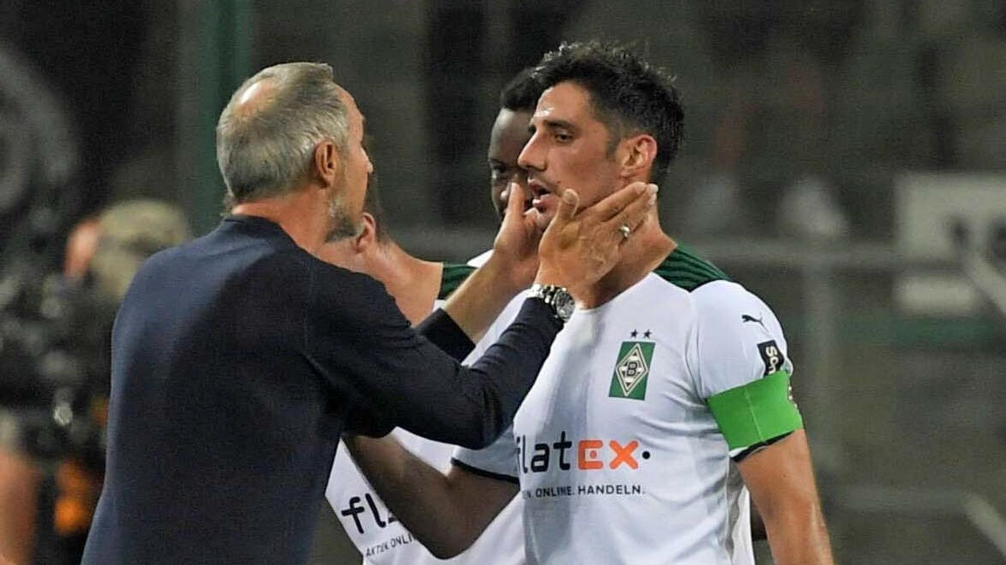 Gladbach-Coach Adi Hütter (l.), jüngst von den Profifußballern in Deutschland zum Trainer der vergangenen Saison gewählt worden, spricht am 12. September 2021 mit seinem Kapitän Lars Stindl, der Borussias Jahrtausend-Torschütze ist. Hütter fasst Stindl mit den Händen ins Gesicht.