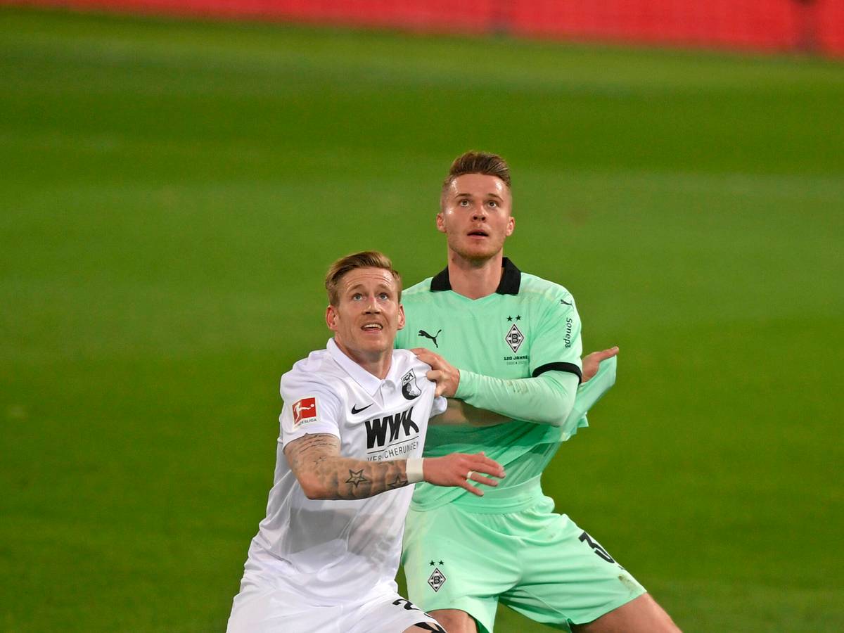 Nico Elvedi (r.), Spieler von Borussia Mönchengladbach und Andre Hahn (l.) blicken im Zweikampf um den Ball nach oben, im Aufeinandertreffen beider Klubs am 12. März 2021.
