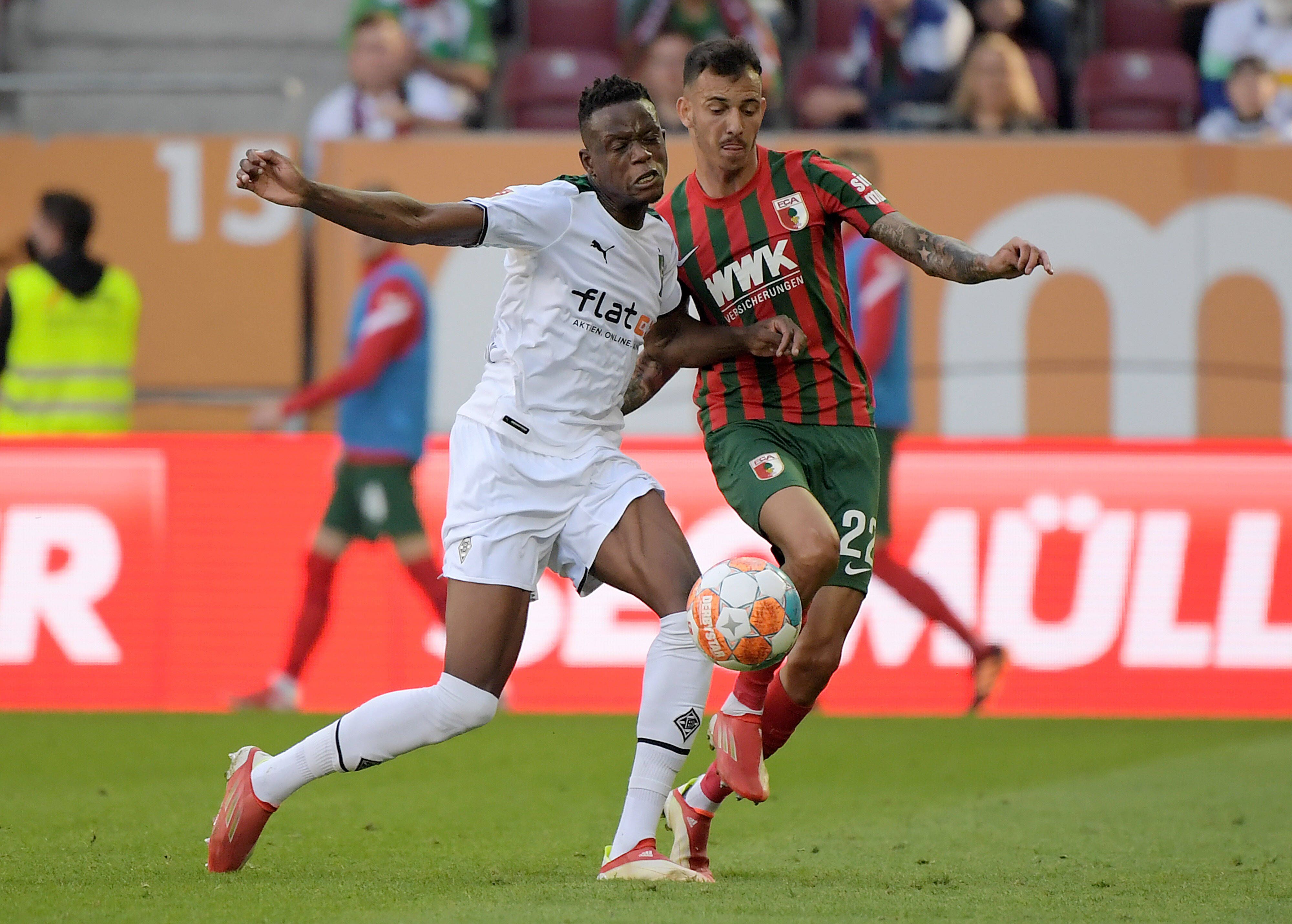 Gladbach-Profi Denis Zakaria (l.) im Duell mit Amaral Borduchi Iago (r.) vom FC Augsburg beim Bundesliga-Duell am 18. September 2021 in der Augsburger Arena. Beide kämpfen um den Ball.