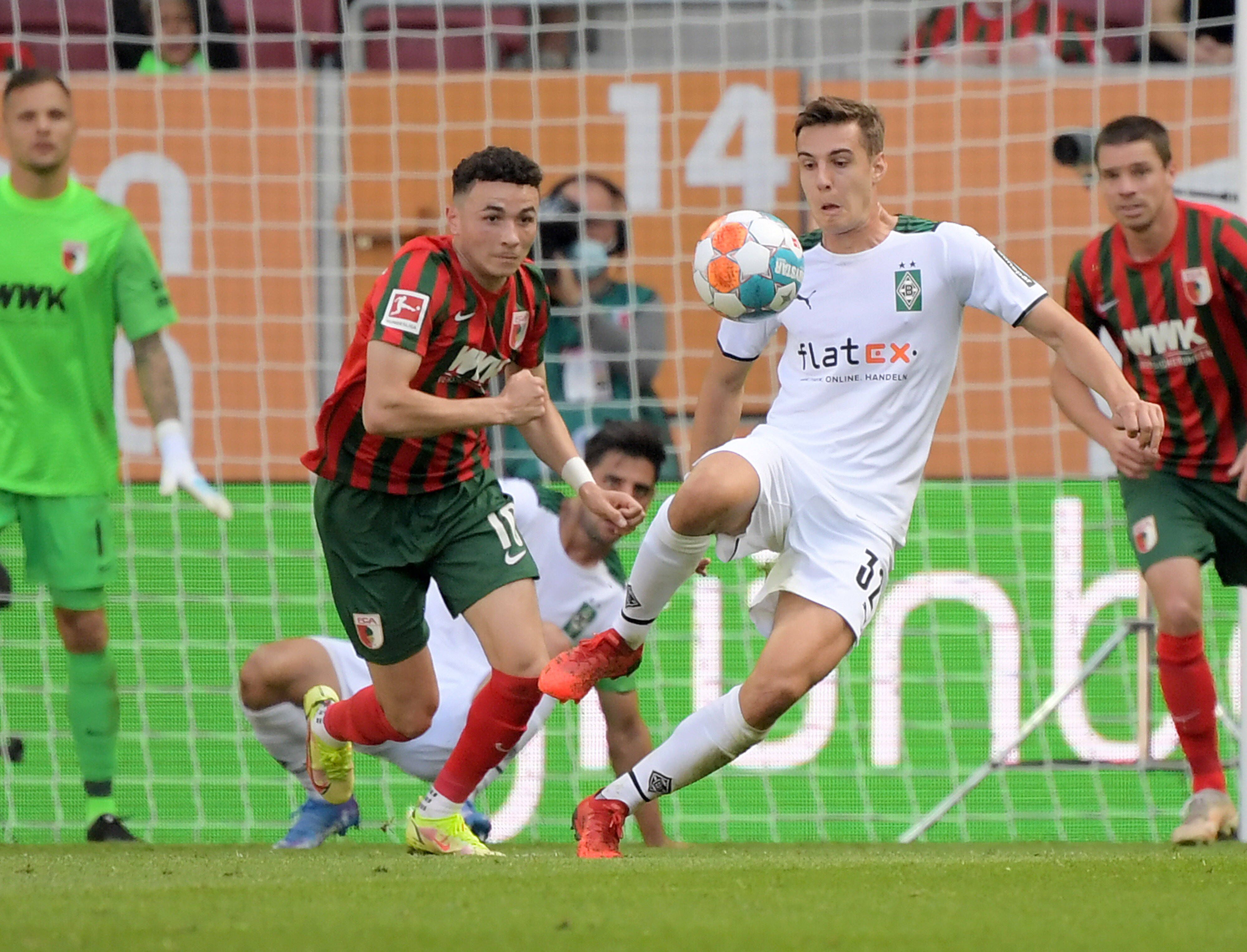 Gladbach-Profi Florian Neuhaus (r.) beim Bundesliga-Spiel in Augsburg am 18. September 2021. In dieser Szene ist Neuhaus im Zweikampf mit Ruben Vargas (l.). Beide Spieler schauen auf den Ball.
