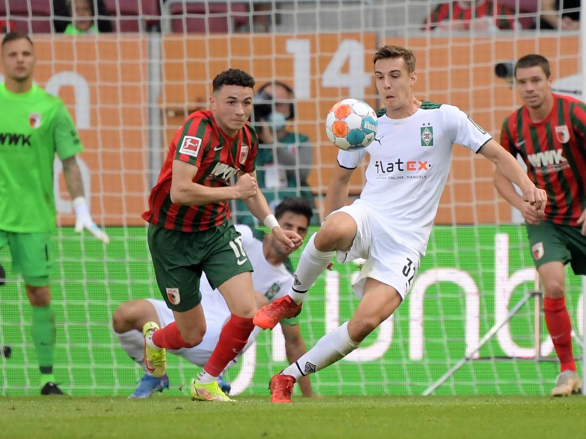 Gladbach-Profi Florian Neuhaus (r.) beim Bundesliga-Spiel in Augsburg am 18. September 2021. In dieser Szene ist Neuhaus im Zweikampf mit Ruben Vargas (l.). Beide Spieler schauen auf den Ball.