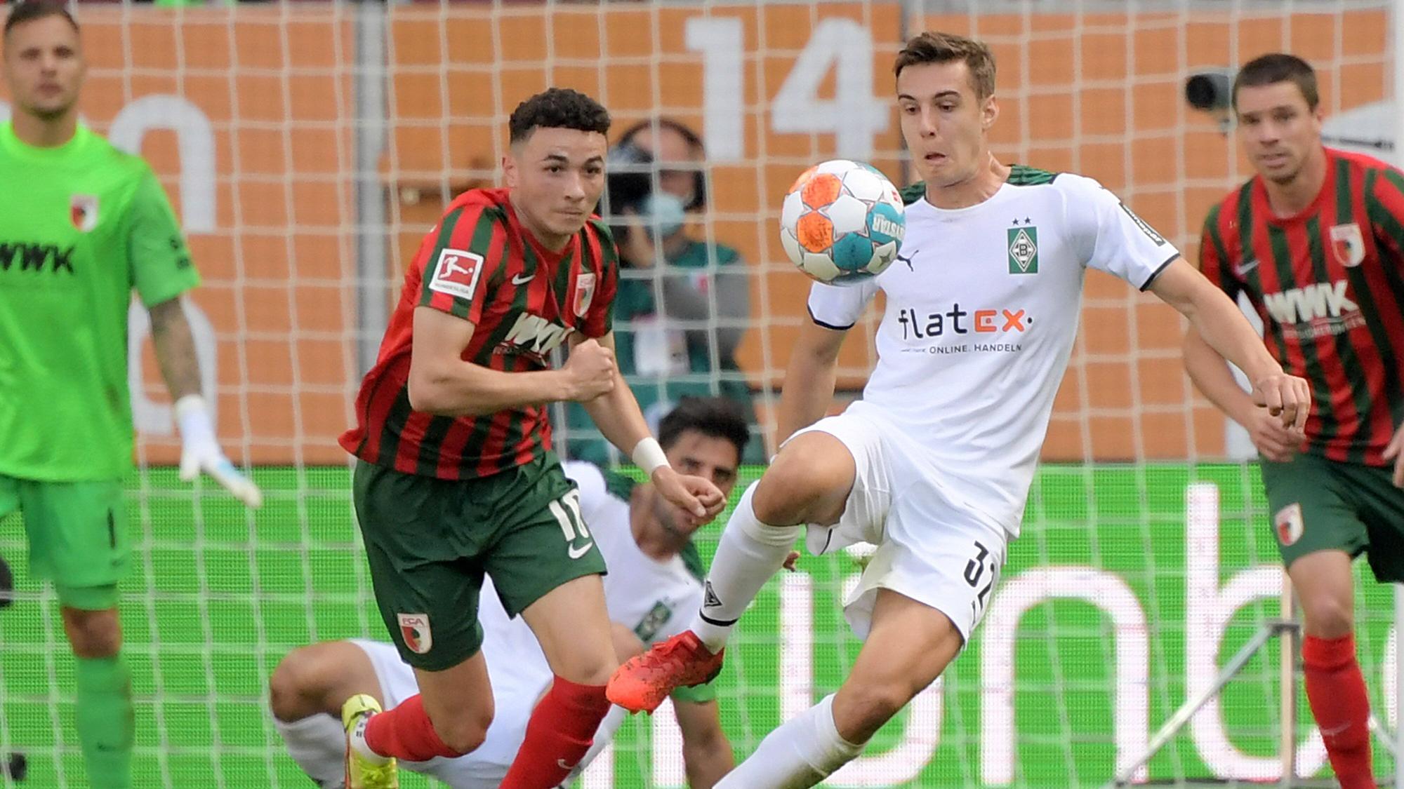 Gladbach-Profi Florian Neuhaus (r.) beim Bundesliga-Spiel in Augsburg am 18. September 2021. In dieser Szene ist Neuhaus im Zweikampf mit Ruben Vargas (l.). Beide Spieler schauen auf den Ball.