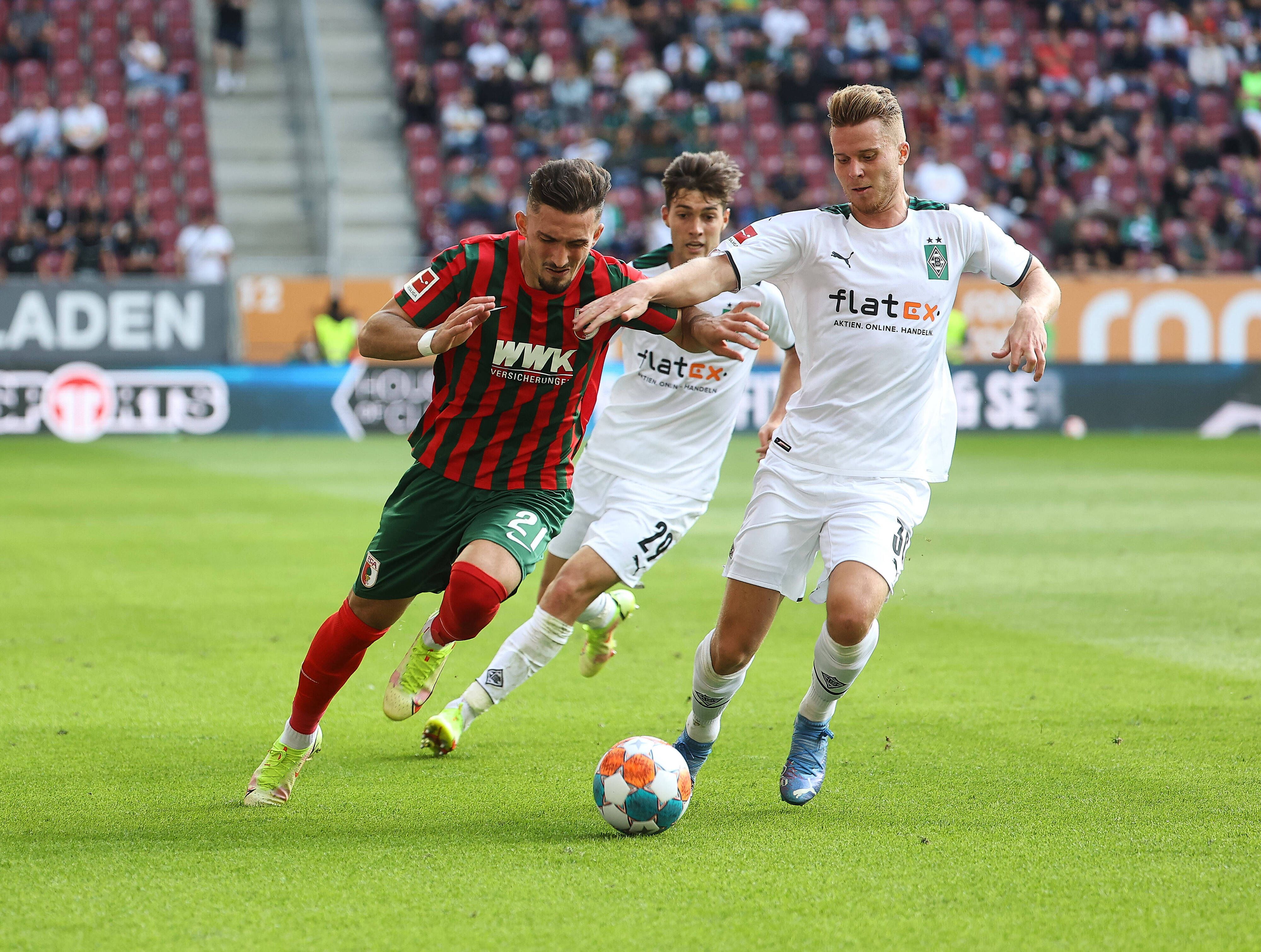 Nico Elvedi, Spieler von Borussia Mönchengladbach im Kampf um den Ball mit Andi Zeqiri vom FC Augsburg am 19. September 2021, dahinter kommt Joe Scally von Gladbach angelaufen.