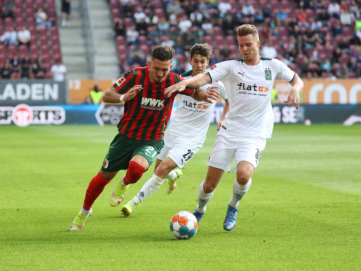 Nico Elvedi, Spieler von Borussia Mönchengladbach im Kampf um den Ball mit Andi Zeqiri vom FC Augsburg am 19. September 2021, dahinter kommt Joe Scally von Gladbach angelaufen.