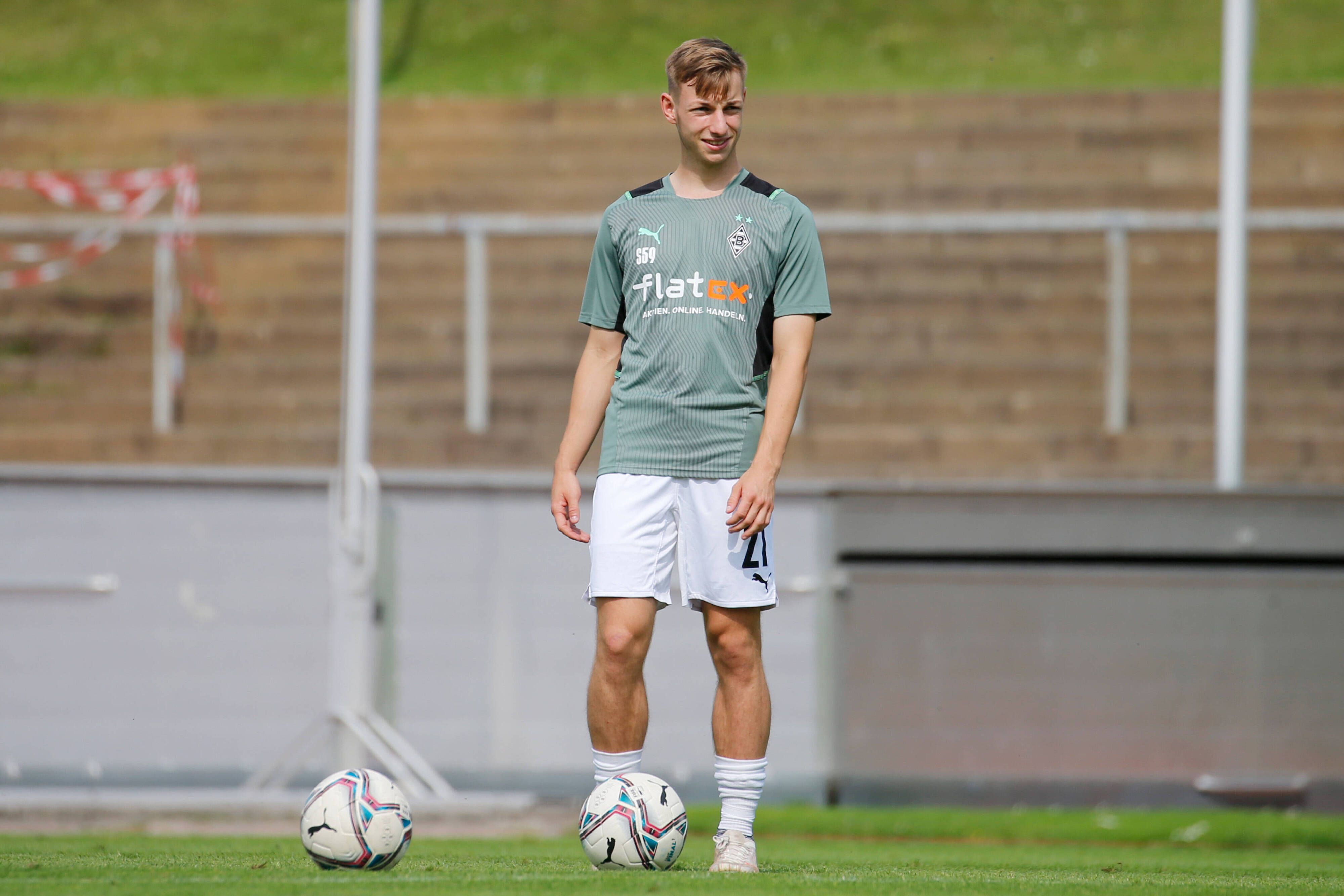 Luiz Skraback von Borussia Mönchengladbach, hier am 21. August 2021, steht lachend mit dem Ball am Fuß auf dem Fußballplatz.