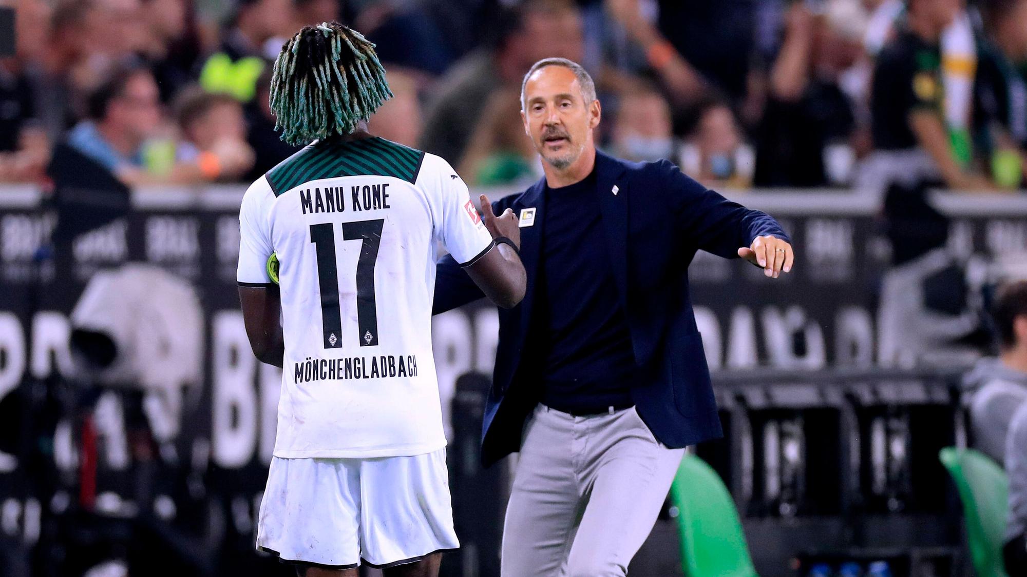 Gladbach-Trainer Adi Hütter (r.) klatscht seinen Mittelfeldspieler Manu Koné (l.) bei dessen Auswechslung während des Bundesliga-Duells mit Dortmund am 25. September 2021 im Borussia-Park ab.