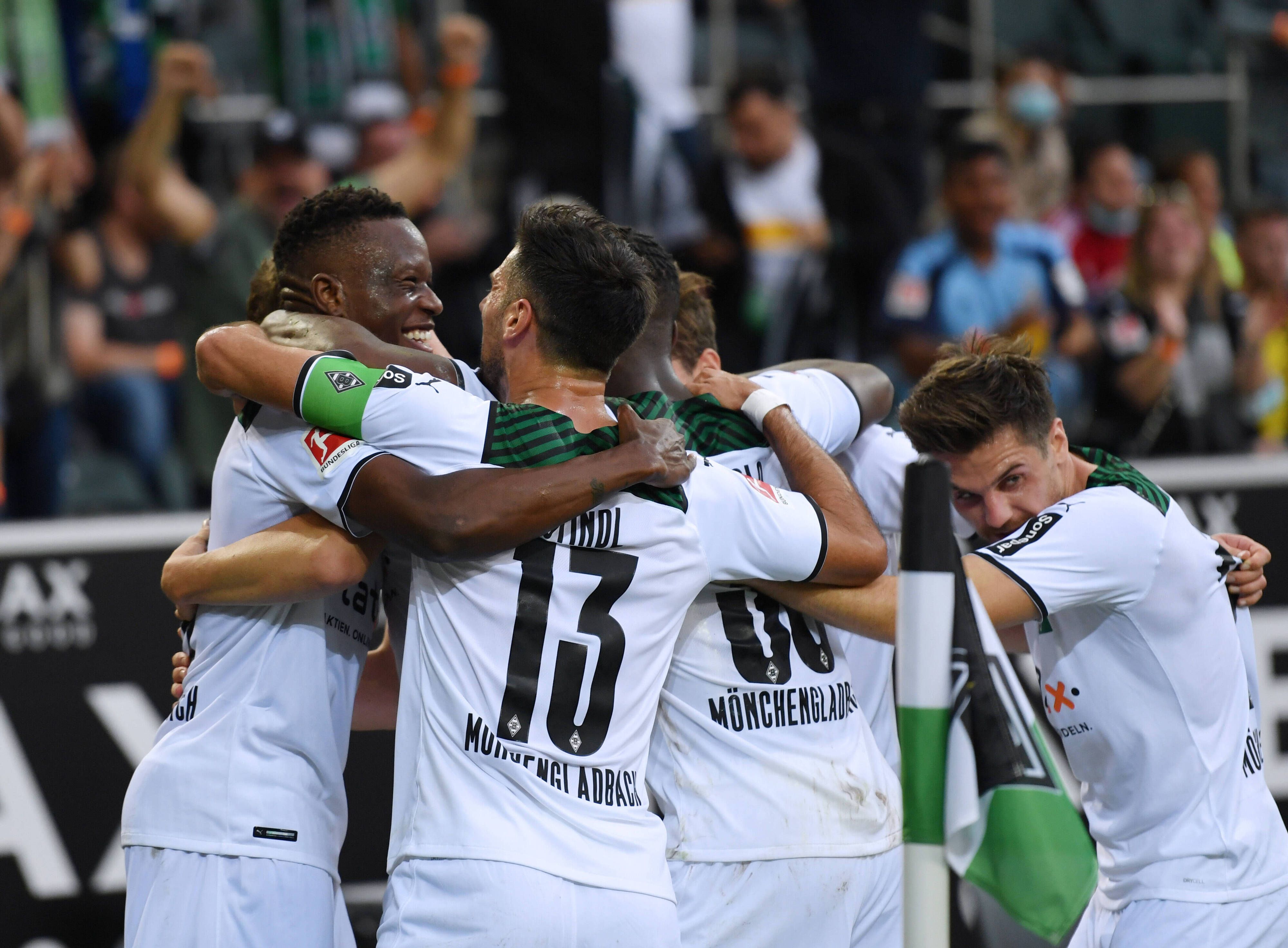 Denis Zakaria und Lars Stindl (v.l.) liegen sich im Arm und bilden mit anderen Spielern von Borussia Mönchengladbach eine Jubeltraube am 25. September 2021.