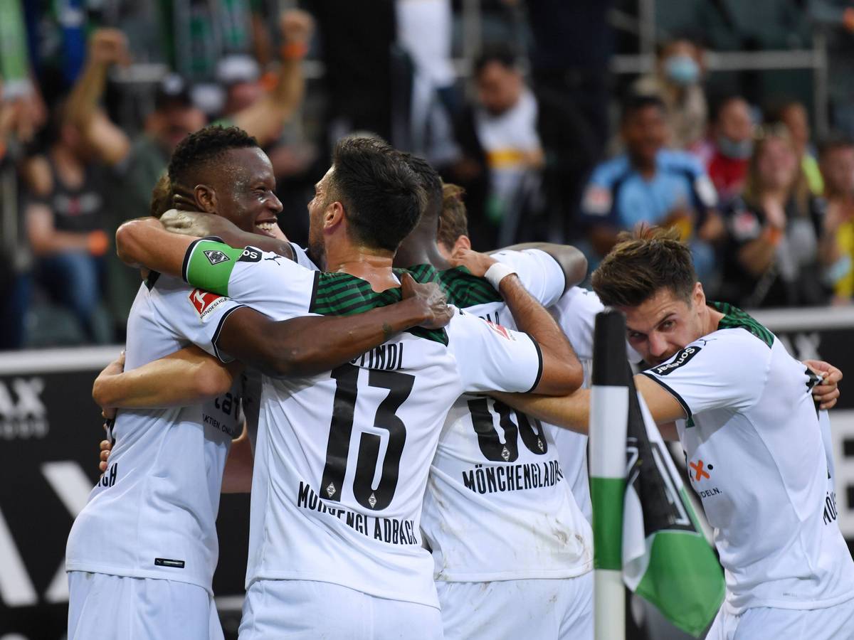 Denis Zakaria und Lars Stindl (v.l.) liegen sich im Arm und bilden mit anderen Spielern von Borussia Mönchengladbach eine Jubeltraube am 25. September 2021.