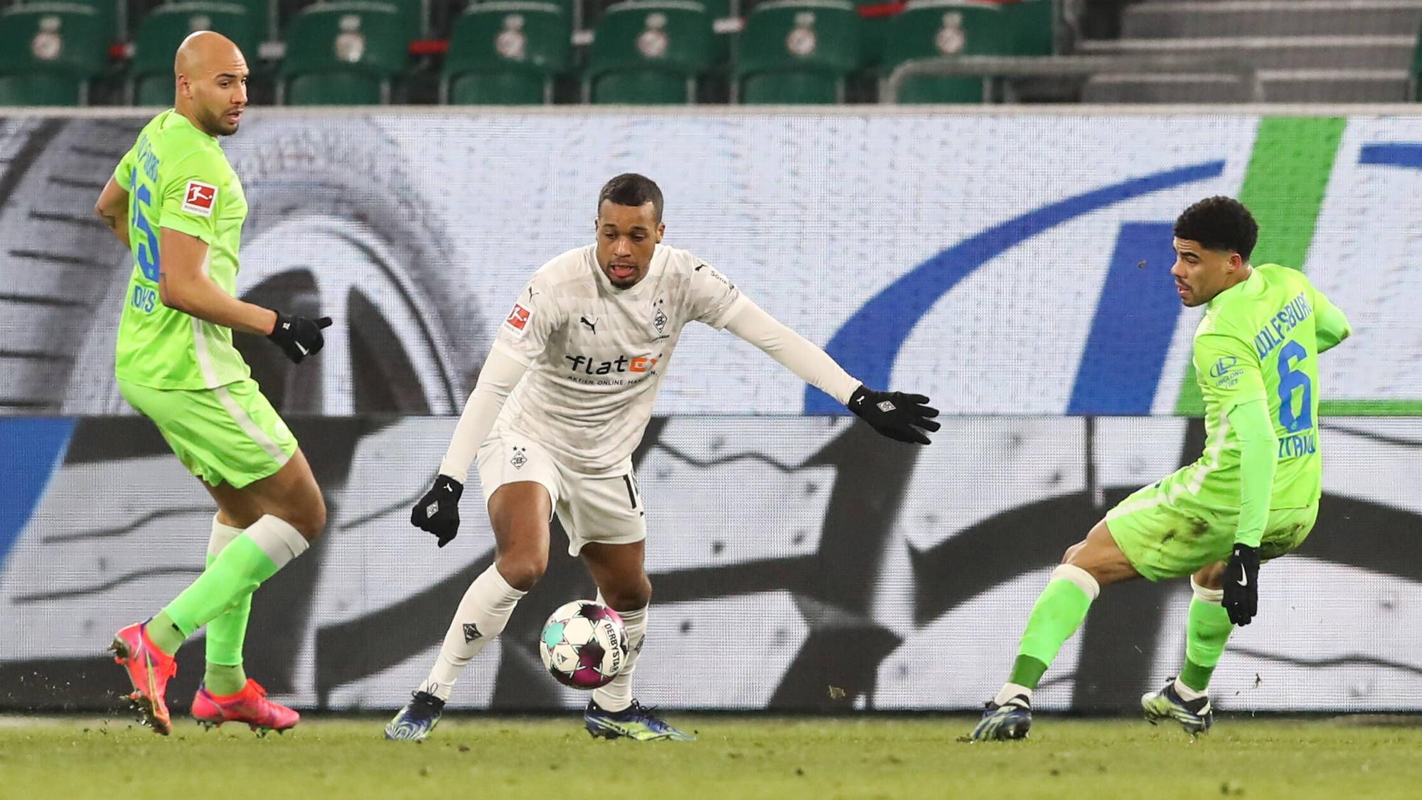 Alassane Plea (Borussia Mönchengladbach,14) im Zweikampf mit John Anthony Brooks und Paulo Otavio (VfL Wolfsburg) am 14. Februar 2021 in der Volkswagen-Arena.