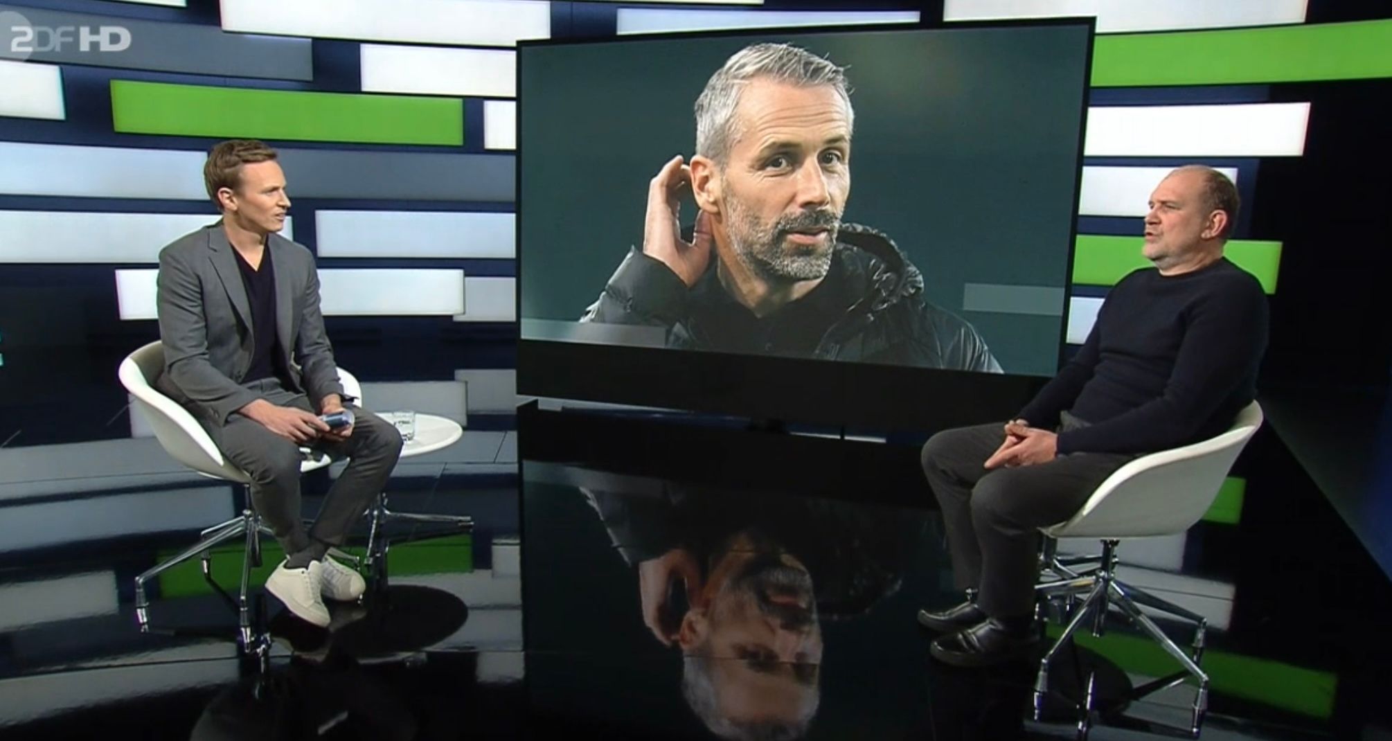 ZDF-Moderator Jochen Breyer (l.) interviewt am 16. Januar 2021 im Sportstudio vor laufenden Kameras den Wolfsburg-Manager Jörg Schmadtke (r.). Auf einem Monitor im Hintergrund ist Gladbach-Trainer Marco Rose zu sehen.