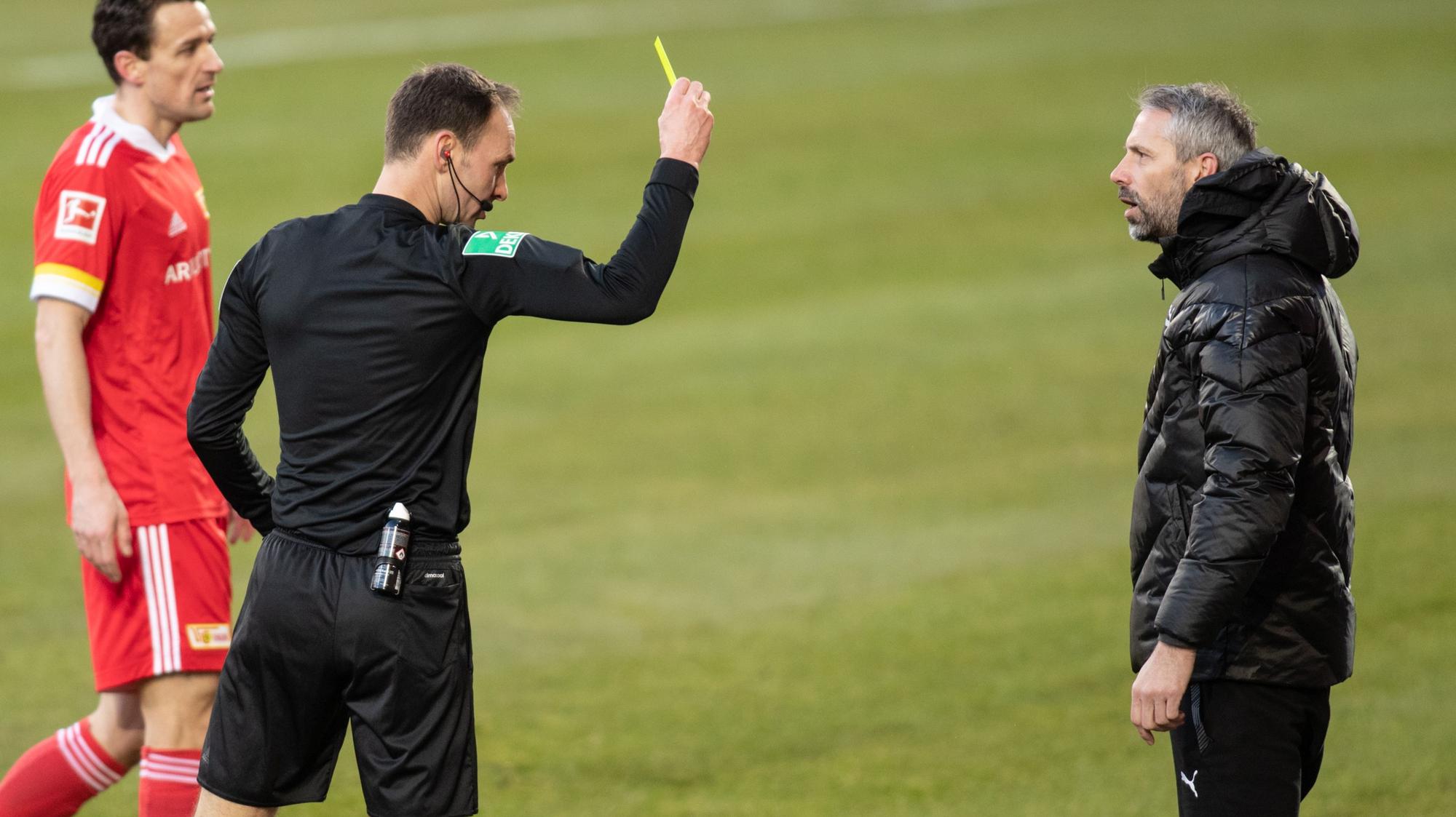 Schiedsrichter Bastian Dankert (M.) zeigt Gladbach-Trainer Marco Rose (r.) die Gelbe Karte am 30. Januar 2021.