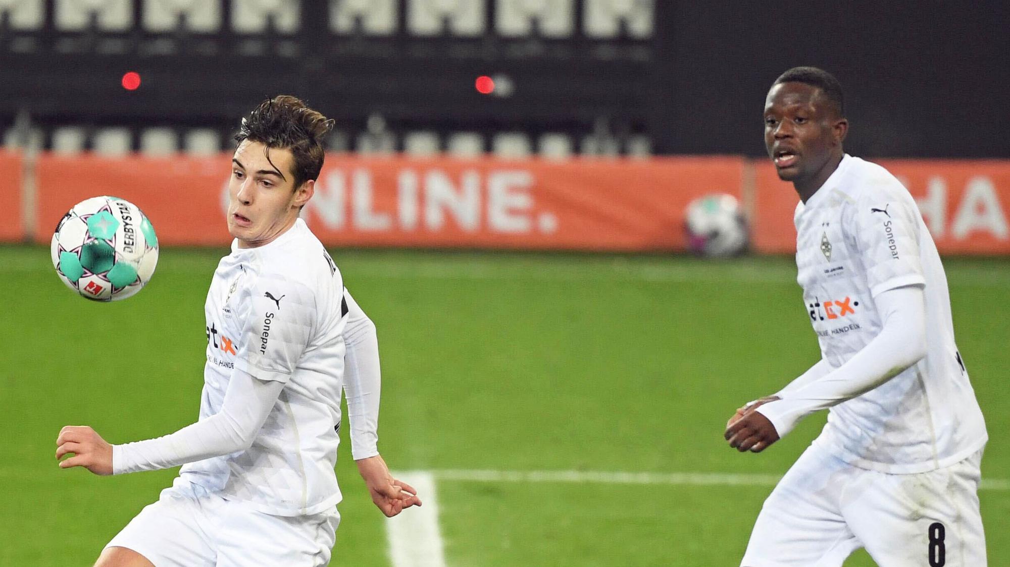 Die Gladbacher Profis Florian Neuhaus (l.) und Denis Zakaria (r.), hier am 28. November 2020 im Bundesliga-Duell gegen Schalke 04 zu sehen, schauen gebannt auf den Ball.