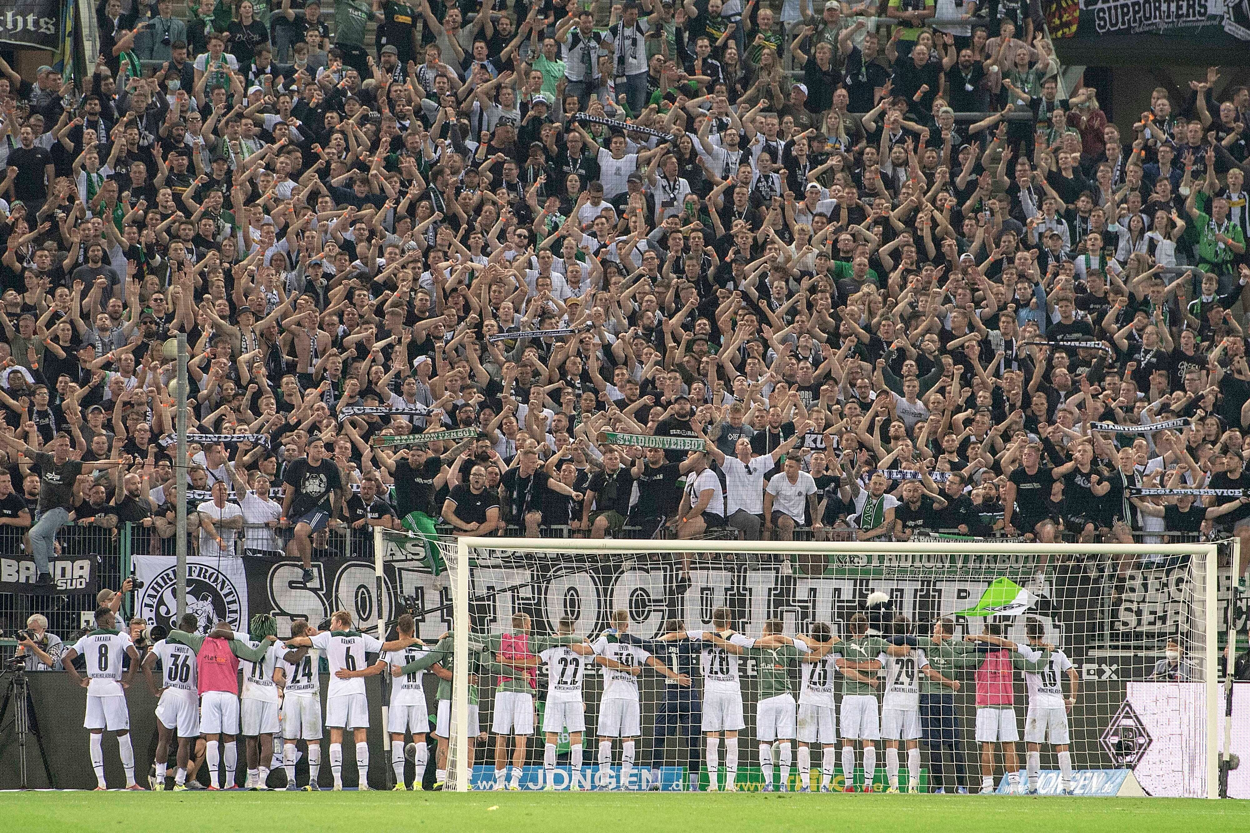 Spieler und Fans von Fußball-Bundesligist Borussia Mönchengladbach feiern gemeinsam nach dem siegreichen Duell gegen Dortmund am 25. September 2021 im Borussia-Park. Die Gladbacher Spieler umarmen sich und stehen vor der Fankurve.