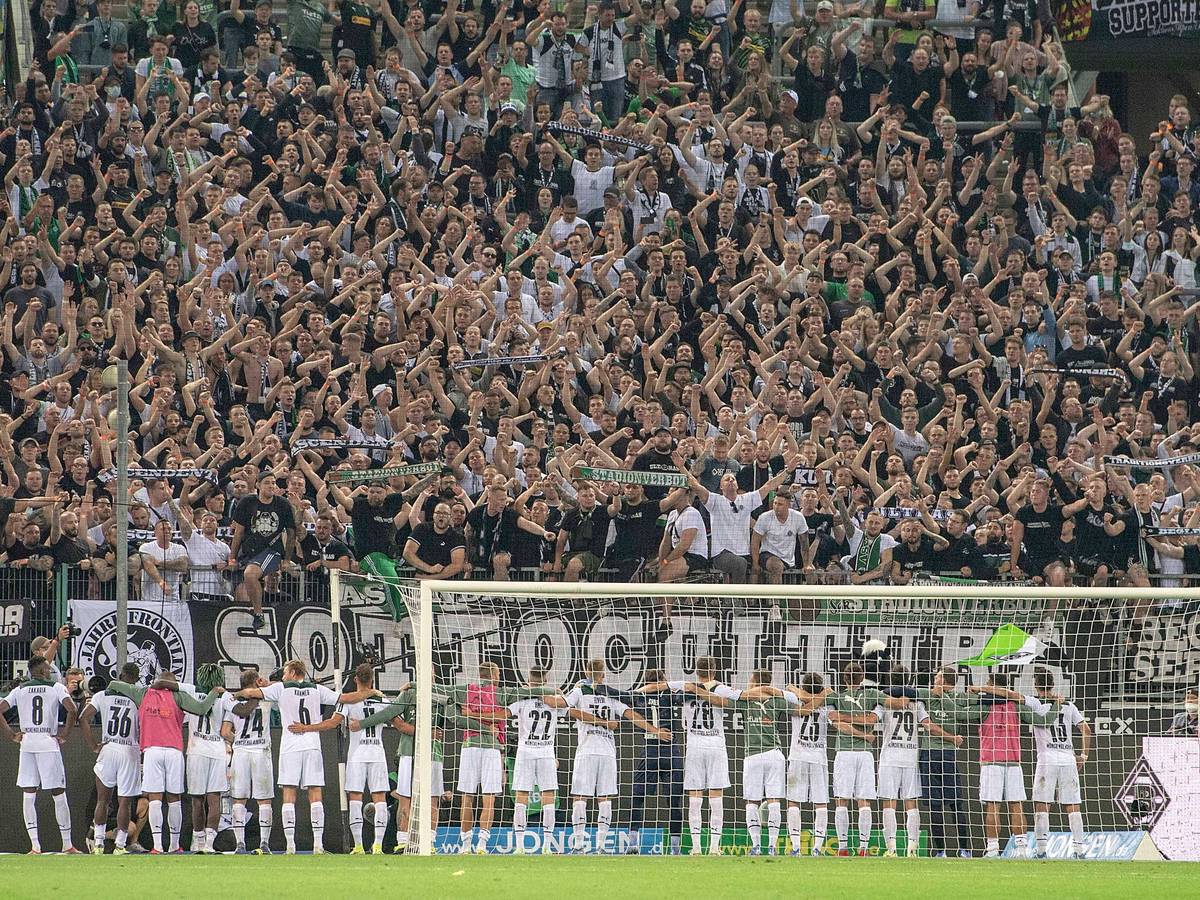 Spieler und Fans von Fußball-Bundesligist Borussia Mönchengladbach feiern gemeinsam nach dem siegreichen Duell gegen Dortmund am 25. September 2021 im Borussia-Park. Die Gladbacher Spieler umarmen sich und stehen vor der Fankurve.