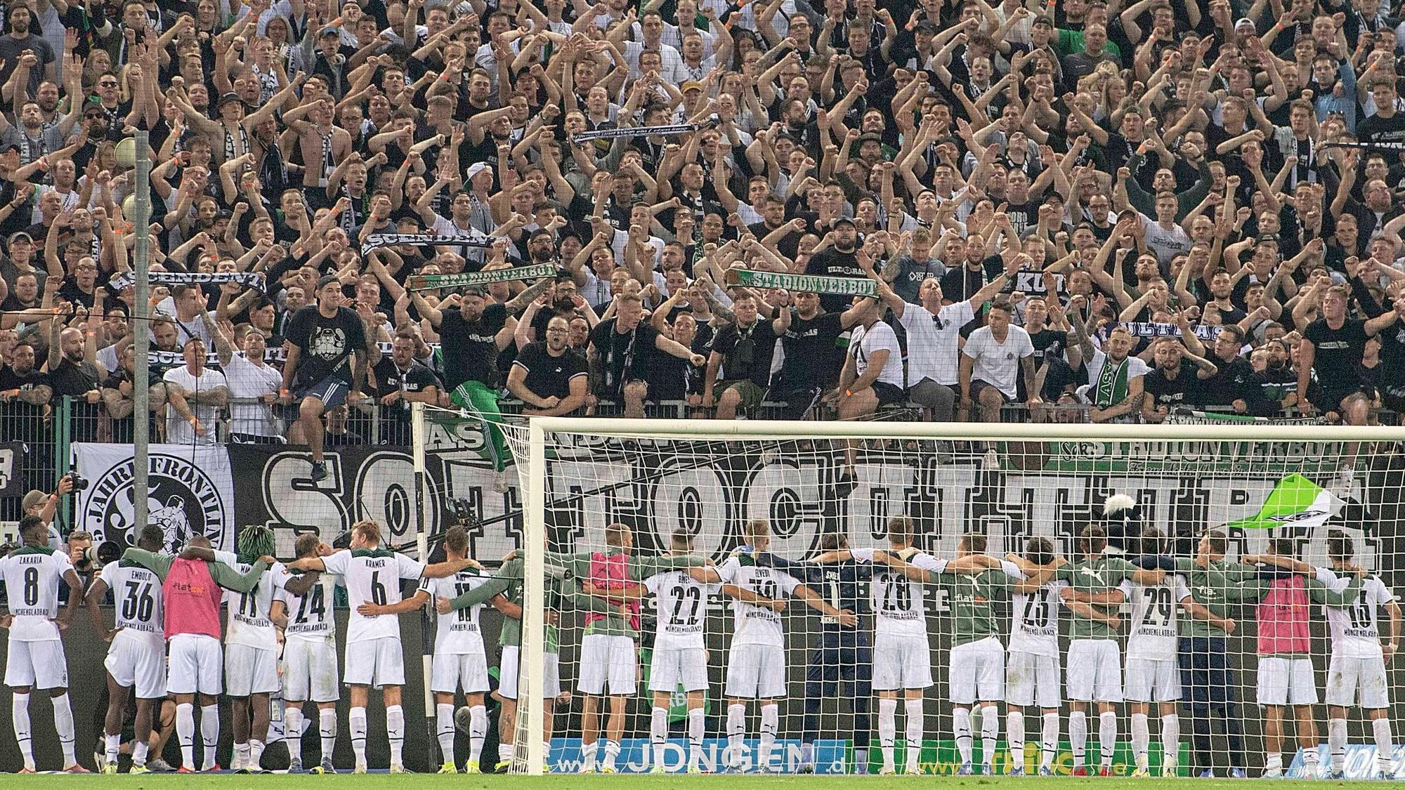 Spieler und Fans von Fußball-Bundesligist Borussia Mönchengladbach feiern gemeinsam nach dem siegreichen Duell gegen Dortmund am 25. September 2021 im Borussia-Park. Die Gladbacher Spieler umarmen sich und stehen vor der Fankurve.