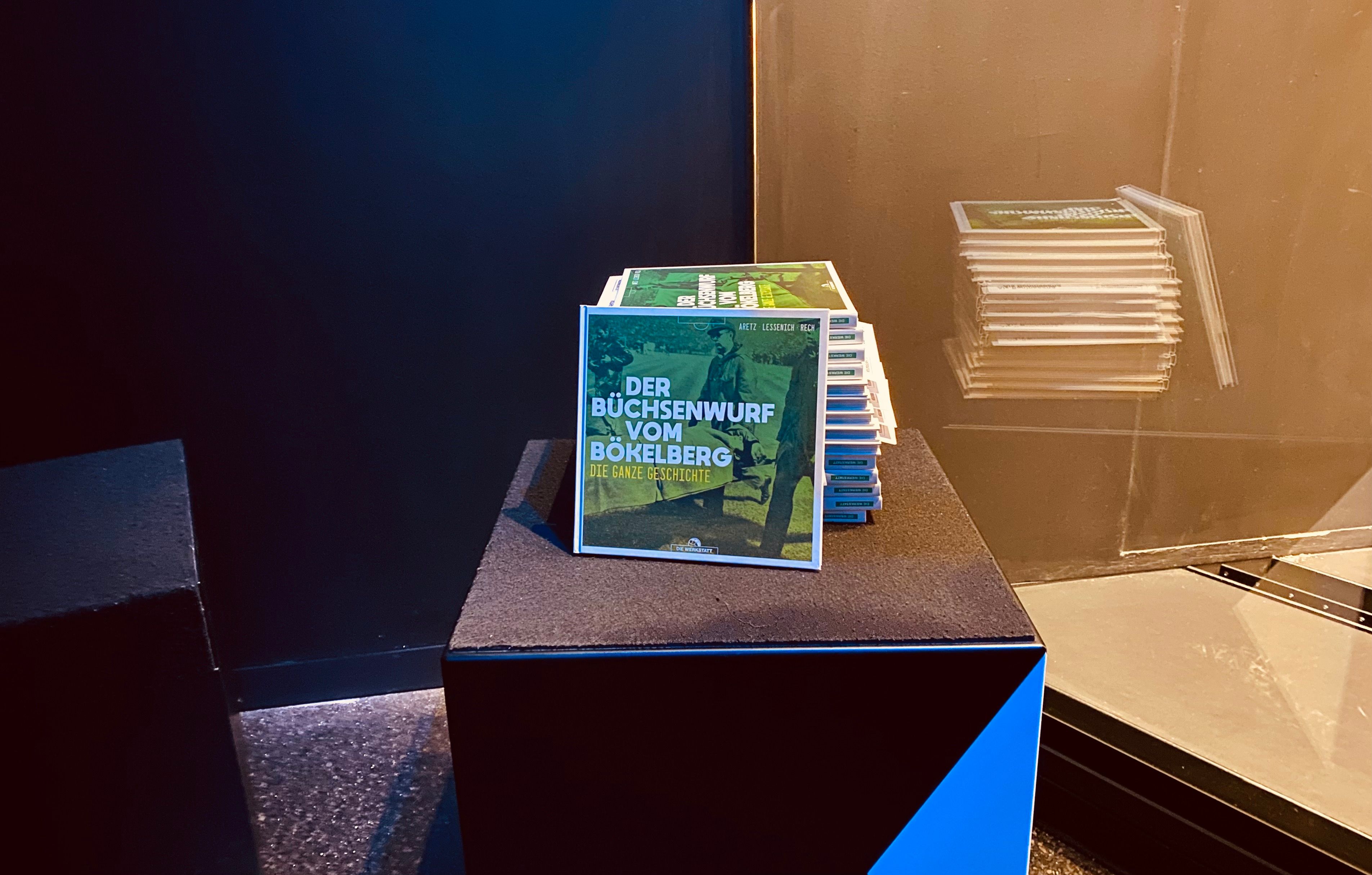 Borussia Mönchengladbach hat am 8. Oktober 2021 im Museum im Borussia-Park das Buch „Der Büchsenwurf vom Bökelberg“ vorgestellt. Mehrere Exemplare  liegen gestapelt auf einem Hocker.