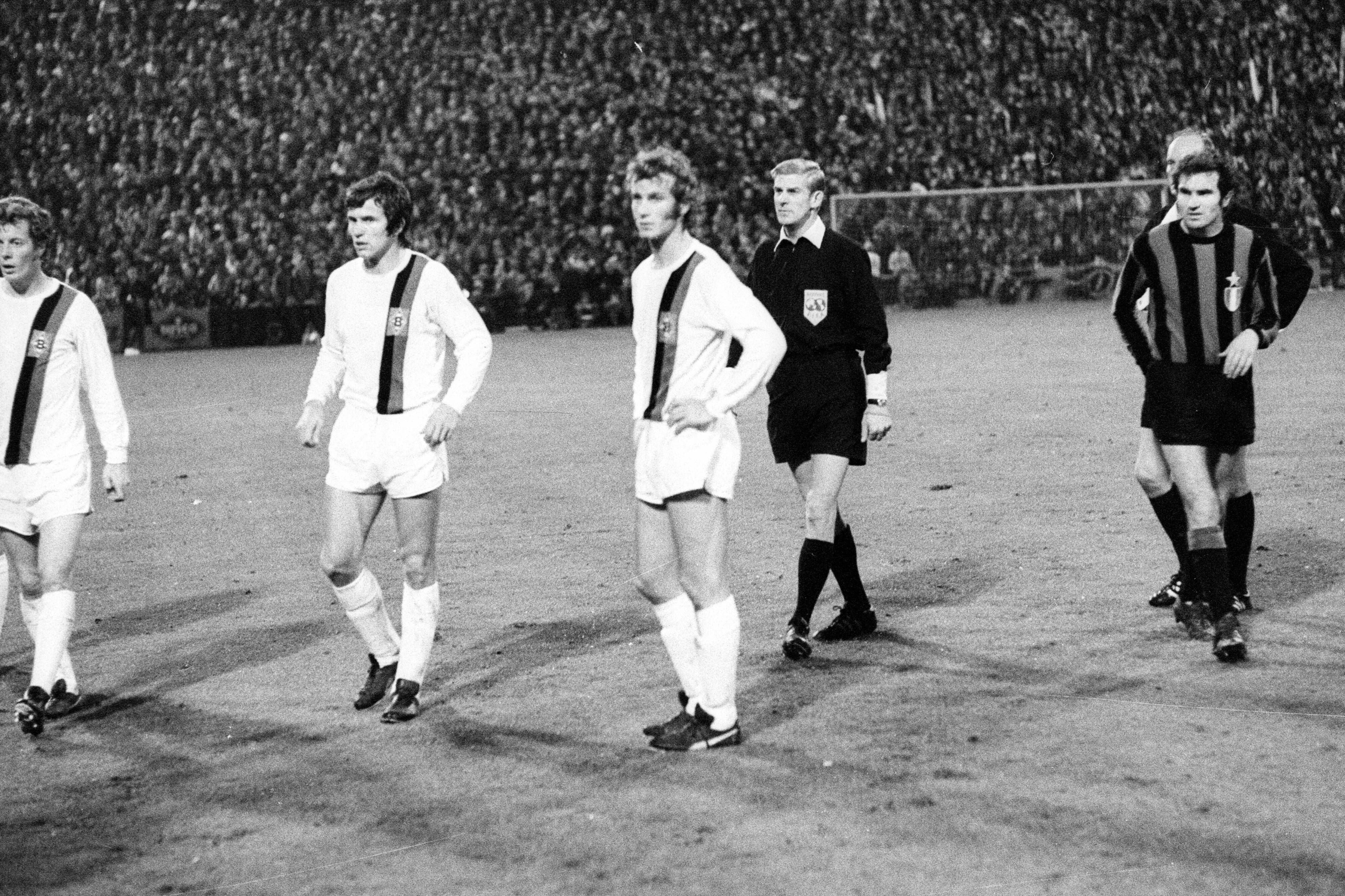 Die Gladbach-Spieler Herbert Wimmer, Jupp Heynckes und Rainer Bonhof (v.li.) verharren auf dem Rasen des Bökelbergstadions. Zuvor hatte eine Cola-Dose den Spieler Roberto Boninsegna von Inter Mailand beim Europapokal-Duell am 20. Oktober 1971 getroffen. Das Spiel endete 7:1 für Gladbach, wurde aber später von der UEFA annulliert.