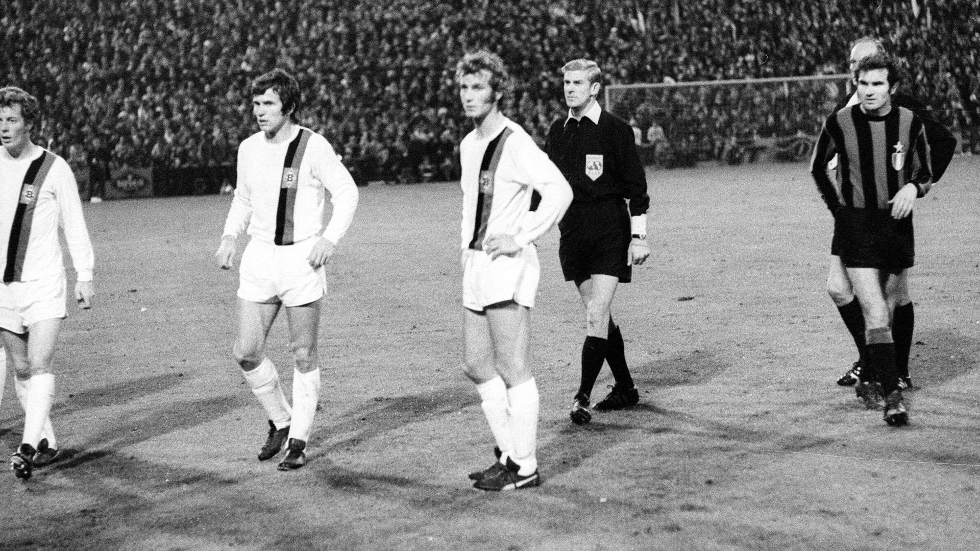 Die Gladbach-Spieler Herbert Wimmer, Jupp Heynckes und Rainer Bonhof (v.li.) verharren auf dem Rasen des Bökelbergstadions. Zuvor hatte eine Cola-Dose den Spieler Roberto Boninsegna von Inter Mailand beim Europapokal-Duell am 20. Oktober 1971 getroffen. Das Spiel endete 7:1 für Gladbach, wurde aber später von der UEFA annulliert.
