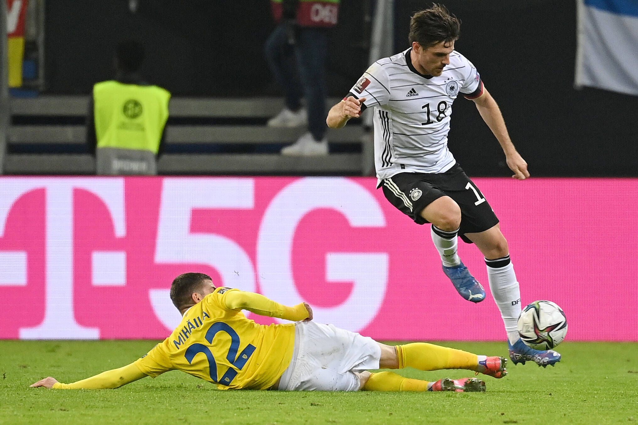 DFB-Nationalspieler Jonas Hofmann (r.), bei Fußball-Bundesligist Borussia Mönchengladbach unter Vertrag, behauptet im Duell mit Valentin Mihaila (l.) den Ball während des Länderspiels gegen Rumänien am 8. Oktober 2021 in Hamburg. Hofmann springt über das Bein des Gegenspielers.