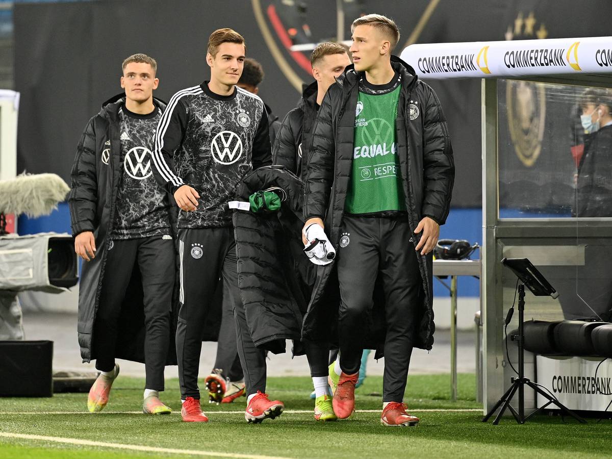 Die Nationalspieler Florian, Florian Neuhaus und Nico Schlotterbeck (v.l.n.r.) schreiten am 8. Oktober 2021 in Hamburg zur Reservebank der DFB-Elf. Neuhaus hält seinen Mantel in der Hand.