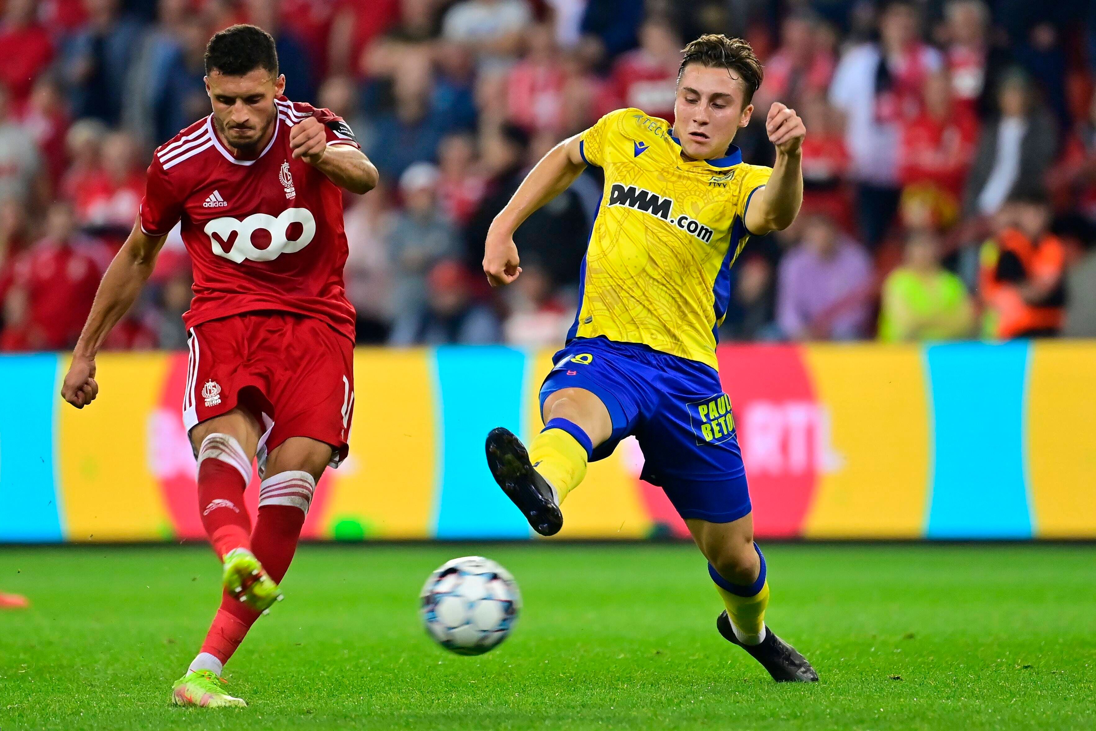 Borussia Mönchengladbach hat Rocco Reitz (r.) an den belgischen Erstligisten VV St. Truiden ausgeliehen. In dieser Szene ist der Mittelfeldspieler am 25. September 2021 in Lüttich im Duell mit Selim Amallah (l.) von Standard Lüttich zu sehen. Reitz streckt sein Bein aus und will einen Schuss blockieren.