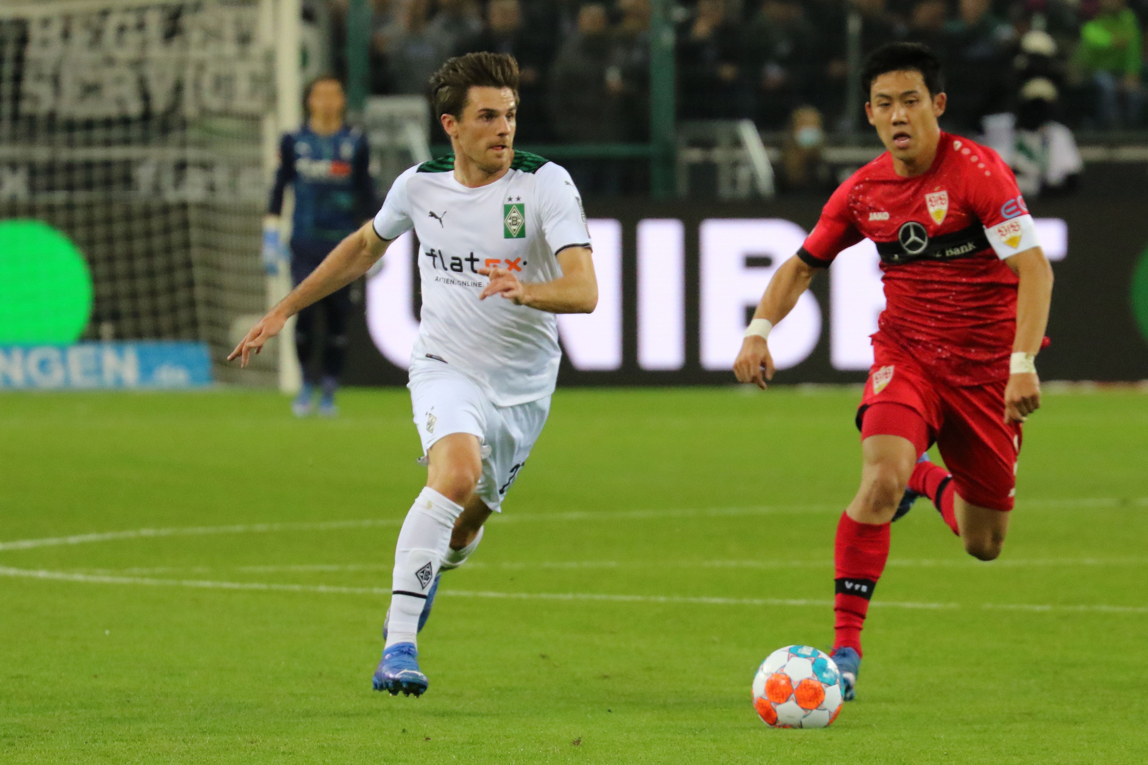 Jonas Hofmann (l.) von Borussia Mönchengladbach im Laufduell mit VfB-Stuttgart-Profi Wataru Endo (r.) am 8. Spieltag der Fußball-Bundesliga (16. Oktober 2021) im Borussia-Park. Beide Spieler wollen den Ball erobern.