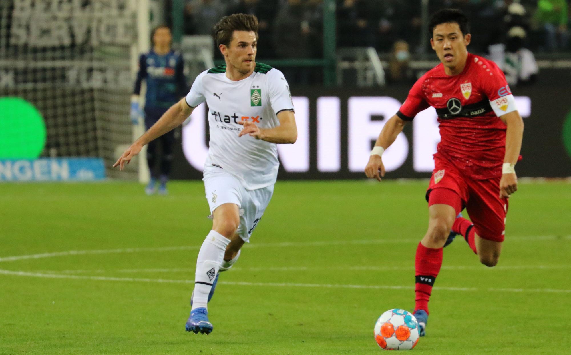 Jonas Hofmann (l.) von Borussia Mönchengladbach im Laufduell mit VfB-Stuttgart-Profi Wataru Endo (r.) am 8. Spieltag der Fußball-Bundesliga (16. Oktober 2021) im Borussia-Park. Beide Spieler wollen den Ball erobern.