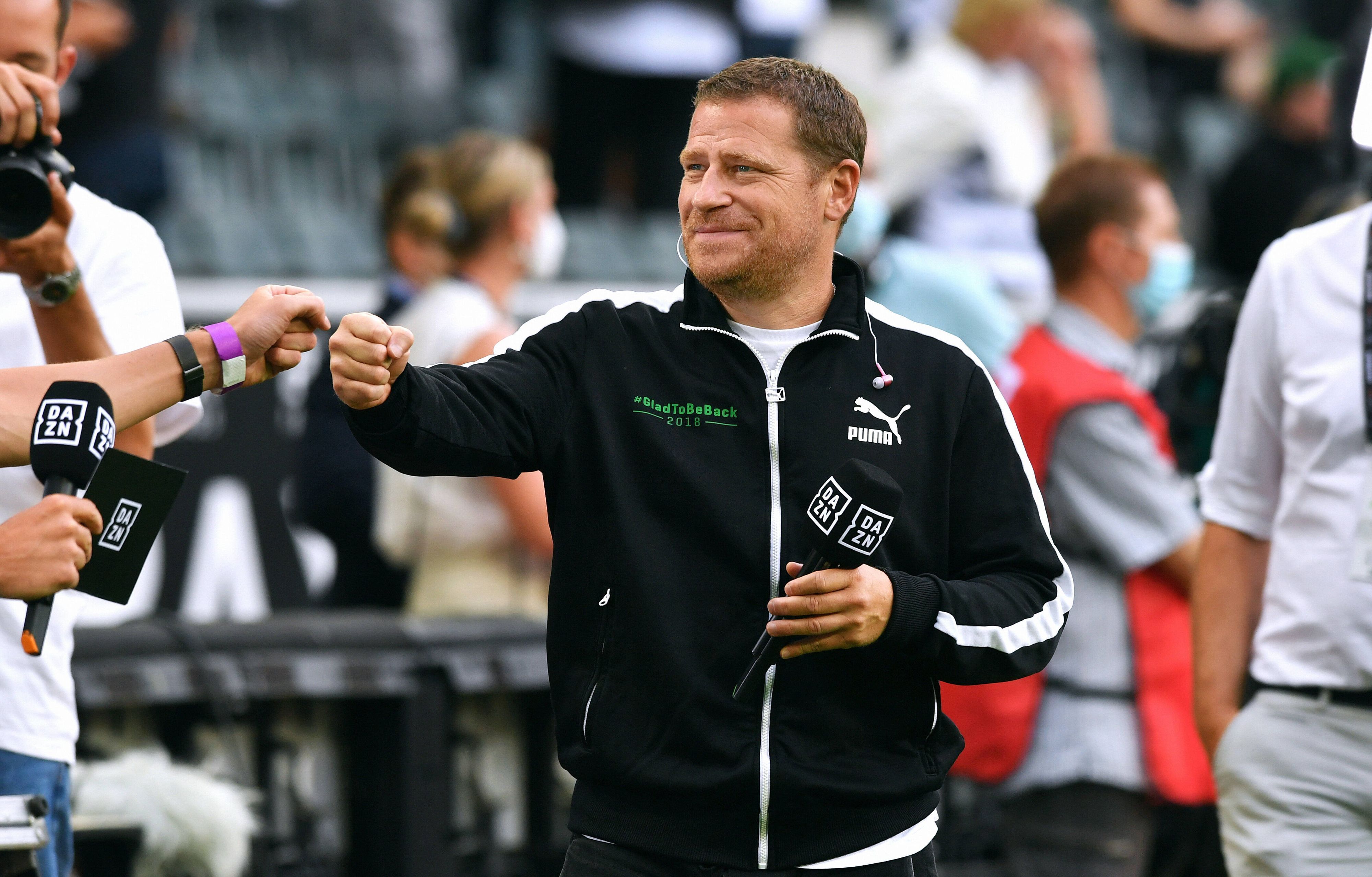 Max Eberl, Sportdirektor von Borussia Mönchengladbach, hier am 13. August 2021, hält lächelnd das „DAZN“-Mikro in der Hand und gibt jemandem die Faust.