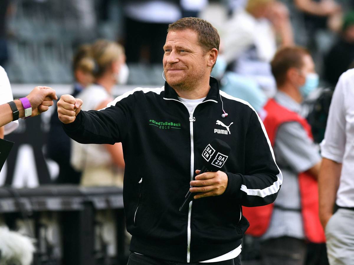 Max Eberl, Sportdirektor von Borussia Mönchengladbach, hier am 13. August 2021, hält lächelnd das „DAZN“-Mikro in der Hand und gibt jemandem die Faust.