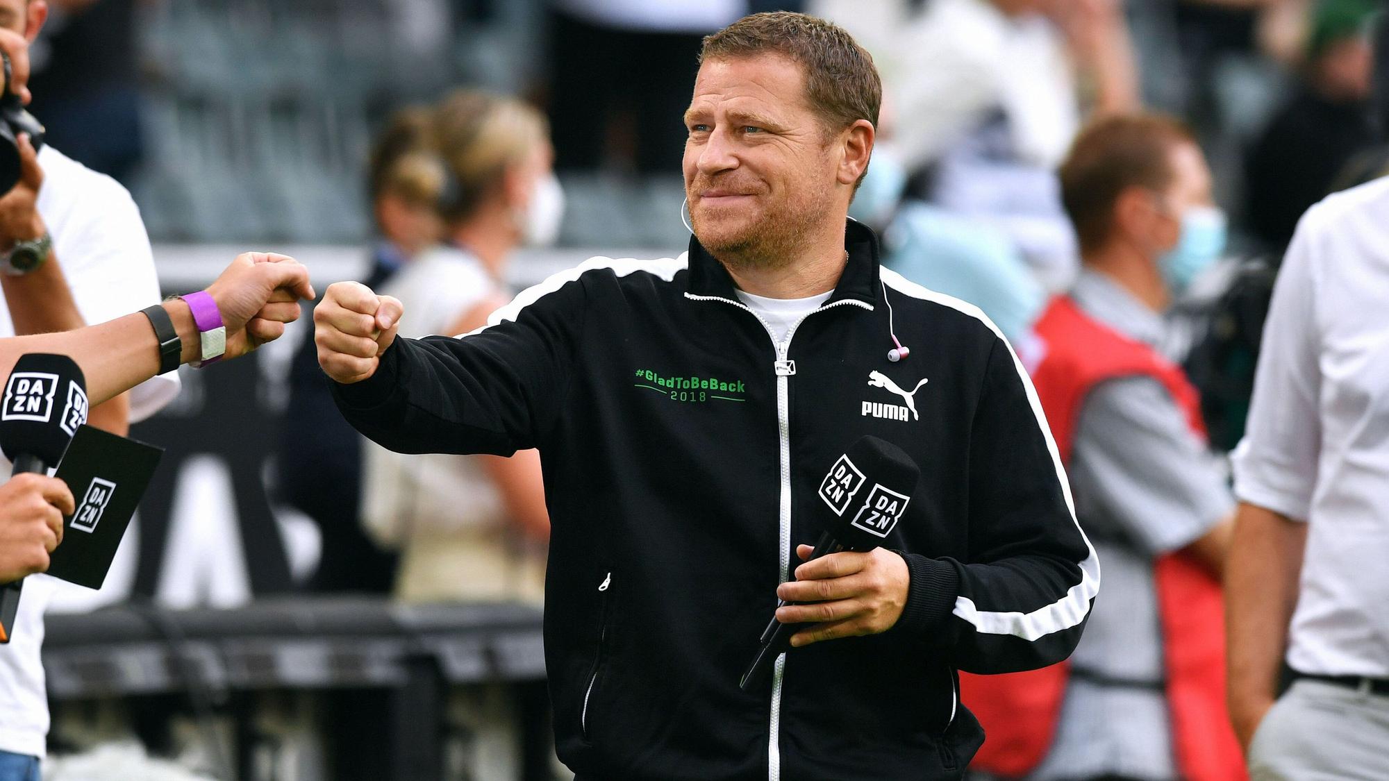 Max Eberl, Sportdirektor von Borussia Mönchengladbach, hier am 13. August 2021, hält lächelnd das „DAZN“-Mikro in der Hand und gibt jemandem die Faust.