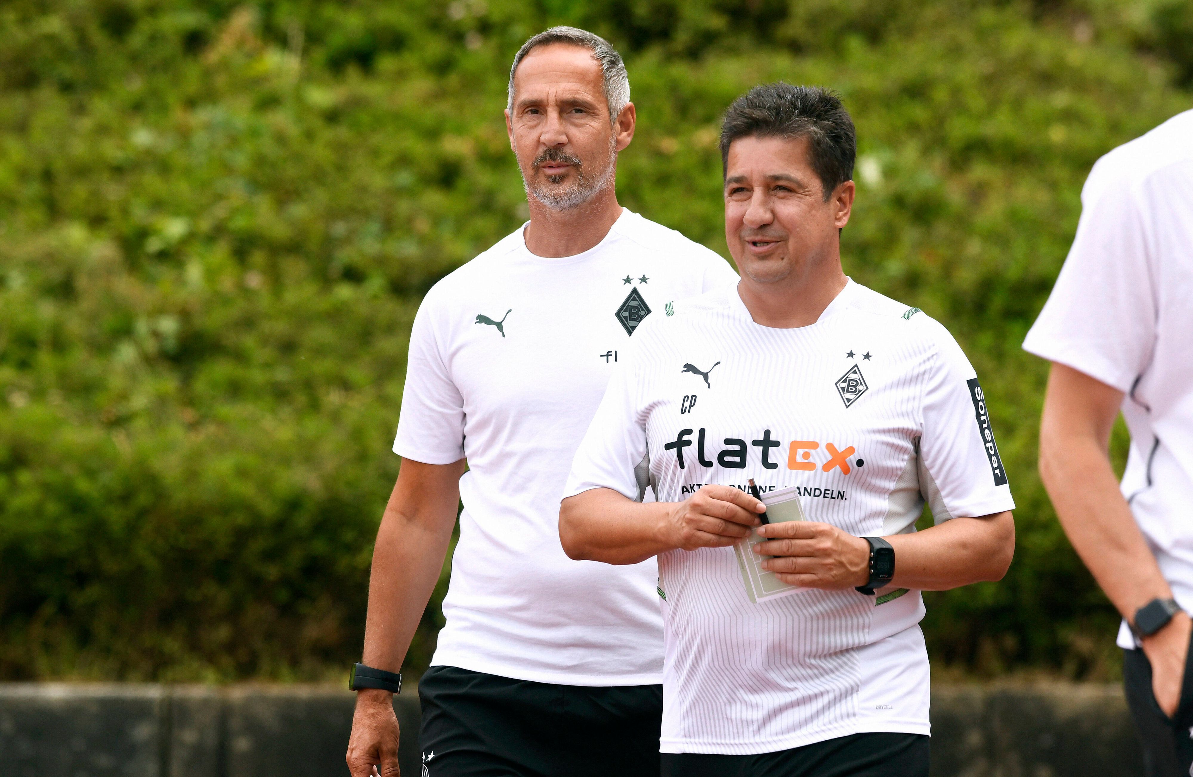 Adi Hütter (l.), Cheftrainer von Fußball-Bundesligist Borussia Mönchengladbach, und sein Co-Trainer Christian Peintinger (r.) am 10. Juli 2021 beim Testspiel der Fohlen gegen Viktoria Köln im Rheydter Grenzlandstadion. Beide Trainer lächeln.