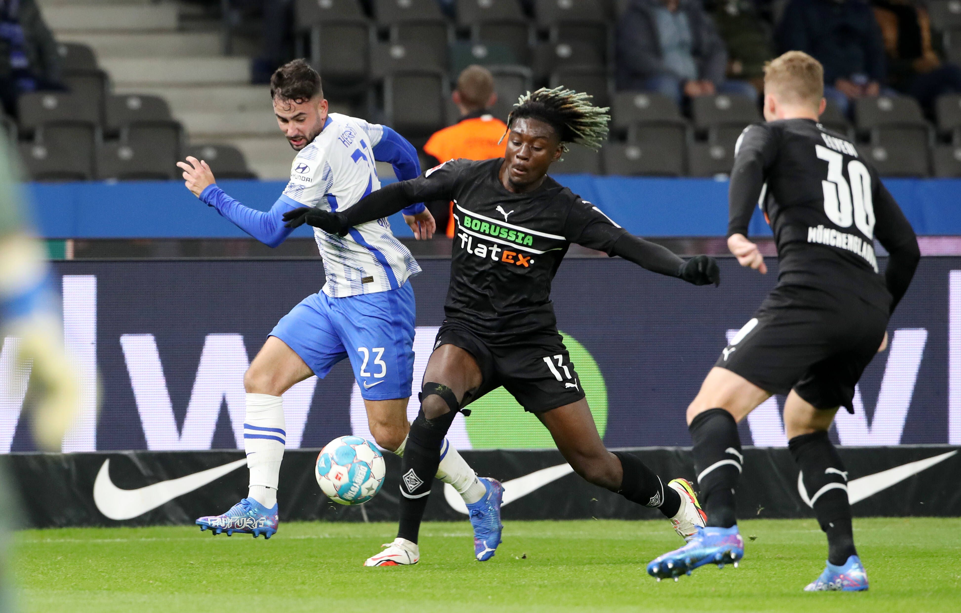 Manu Kone (M.) von Borussia Mönchengladbach im Zweikampf mit Berlins Marco Richter (l.) im Bundesliga-Topspiel am Samstag (23. Oktober 2021) im Olympiastadion. Elvedi rechts beobachtet.
