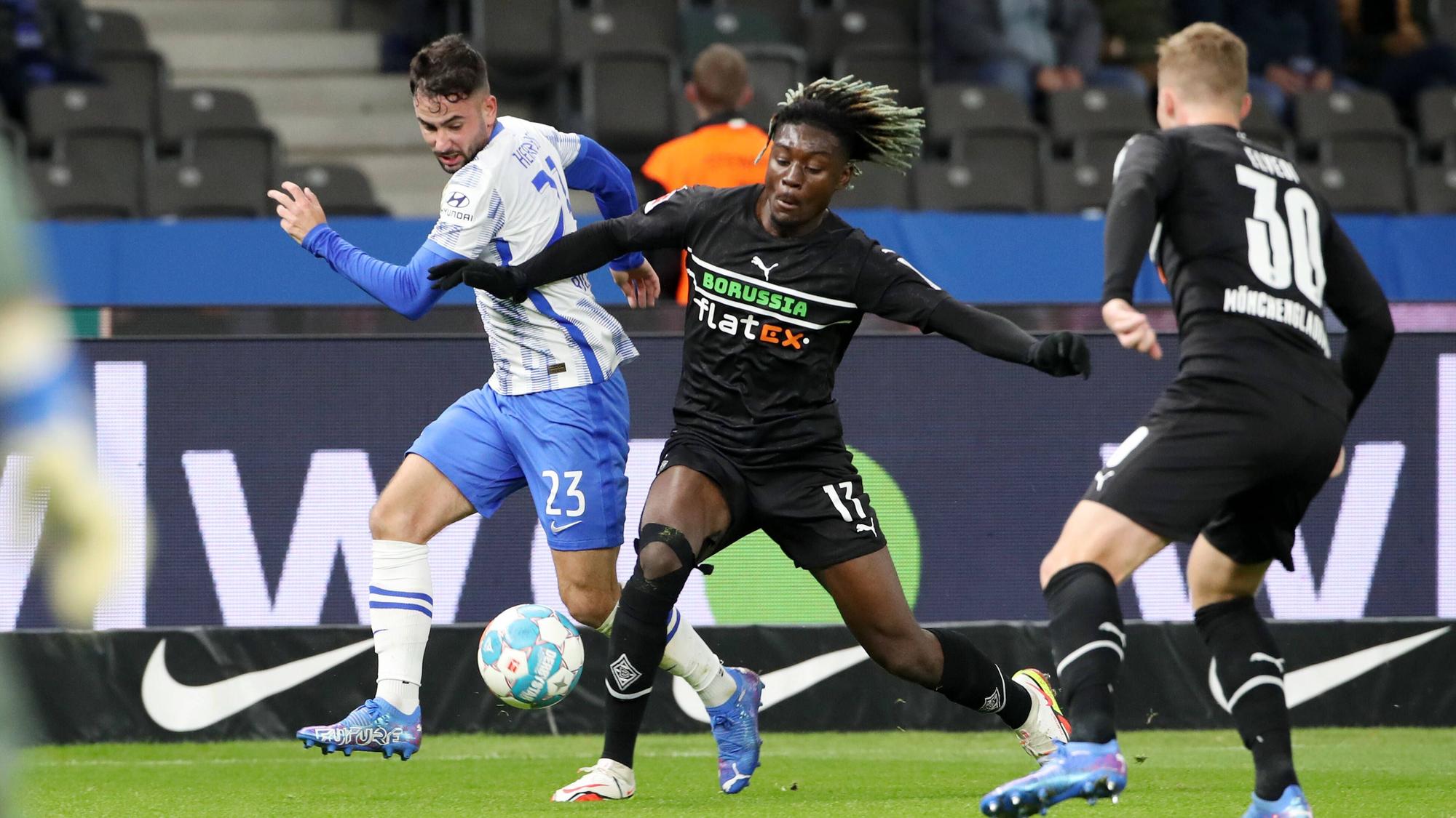 Manu Kone (M.) von Borussia Mönchengladbach im Zweikampf mit Berlins Marco Richter (l.) im Bundesliga-Topspiel am Samstag (23. Oktober 2021) im Olympiastadion. Elvedi rechts beobachtet.