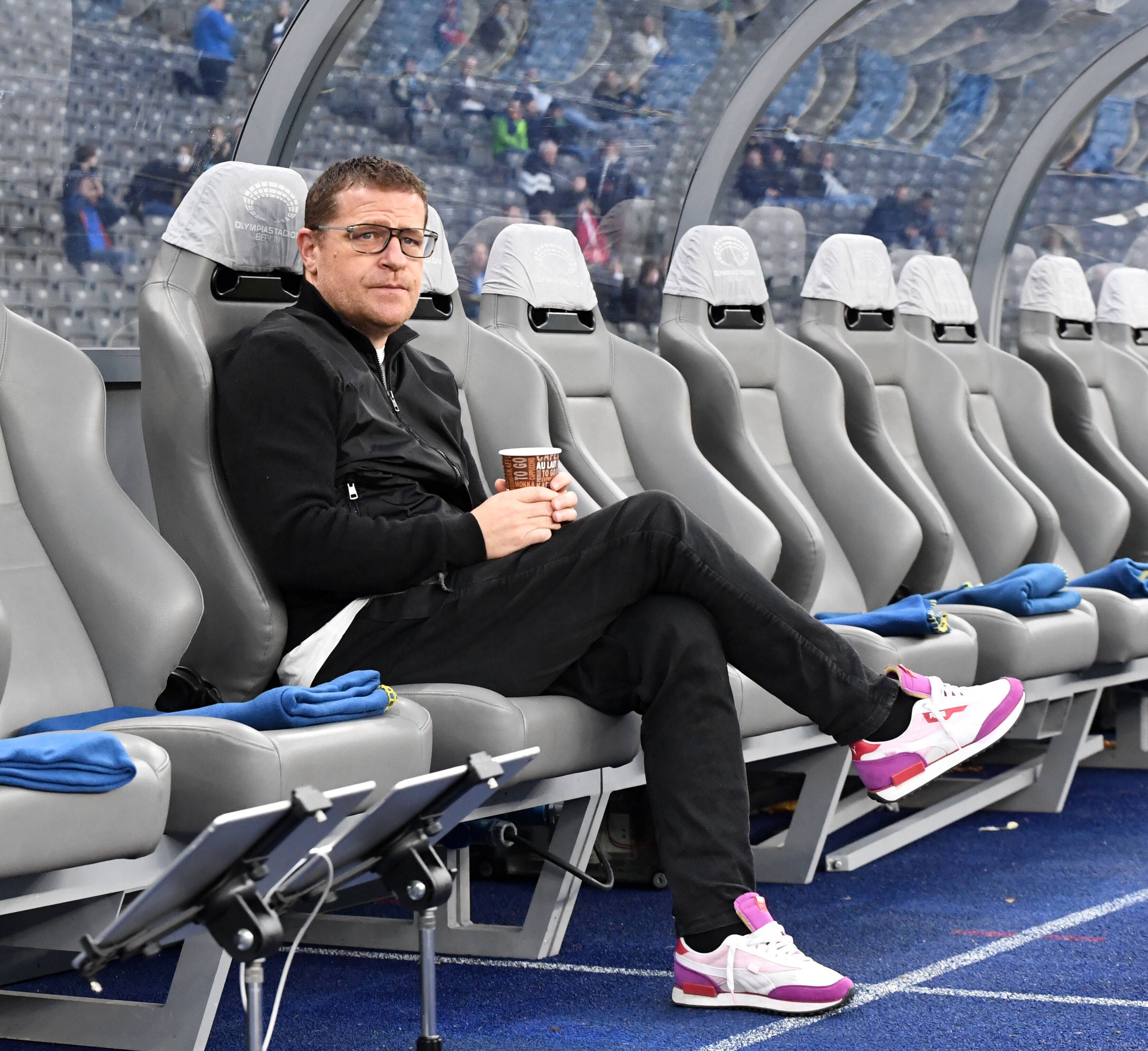 Max Eberl, Manager von Fußball-Bundesligist Borussia Mönchengladbach, sitzt vor dem Topspiel bei Hertha BSC am Samstag (23. Oktober 2021) noch ruhig auf der Ersatzbank im Olympiastadion. Eberl hält einen Getränkebecher in den Händen.
