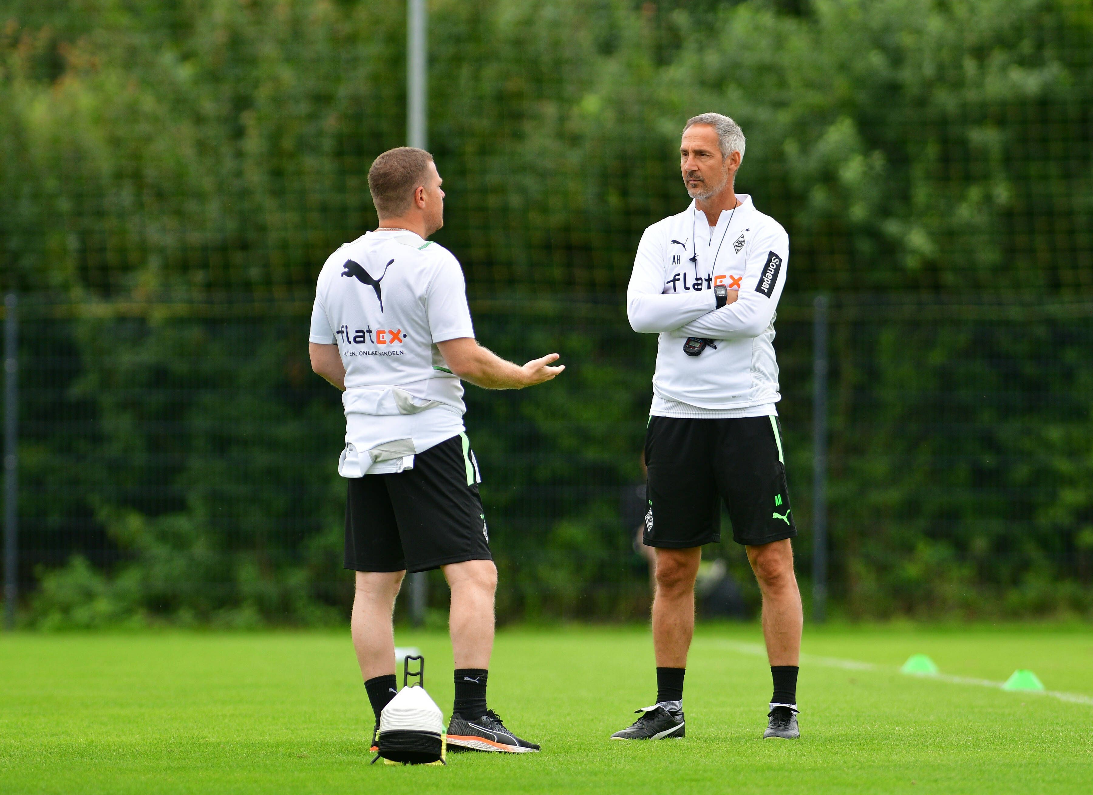 Max Eberl (l.), Manager bei Fußball-Bundesligist Borussia Mönchengladbach, unterhält sich am 21. Juli 2021 in Harsewinkel mit Cheftrainer Adi Hütter (r.). Eberl redet, Hütter hört zu.