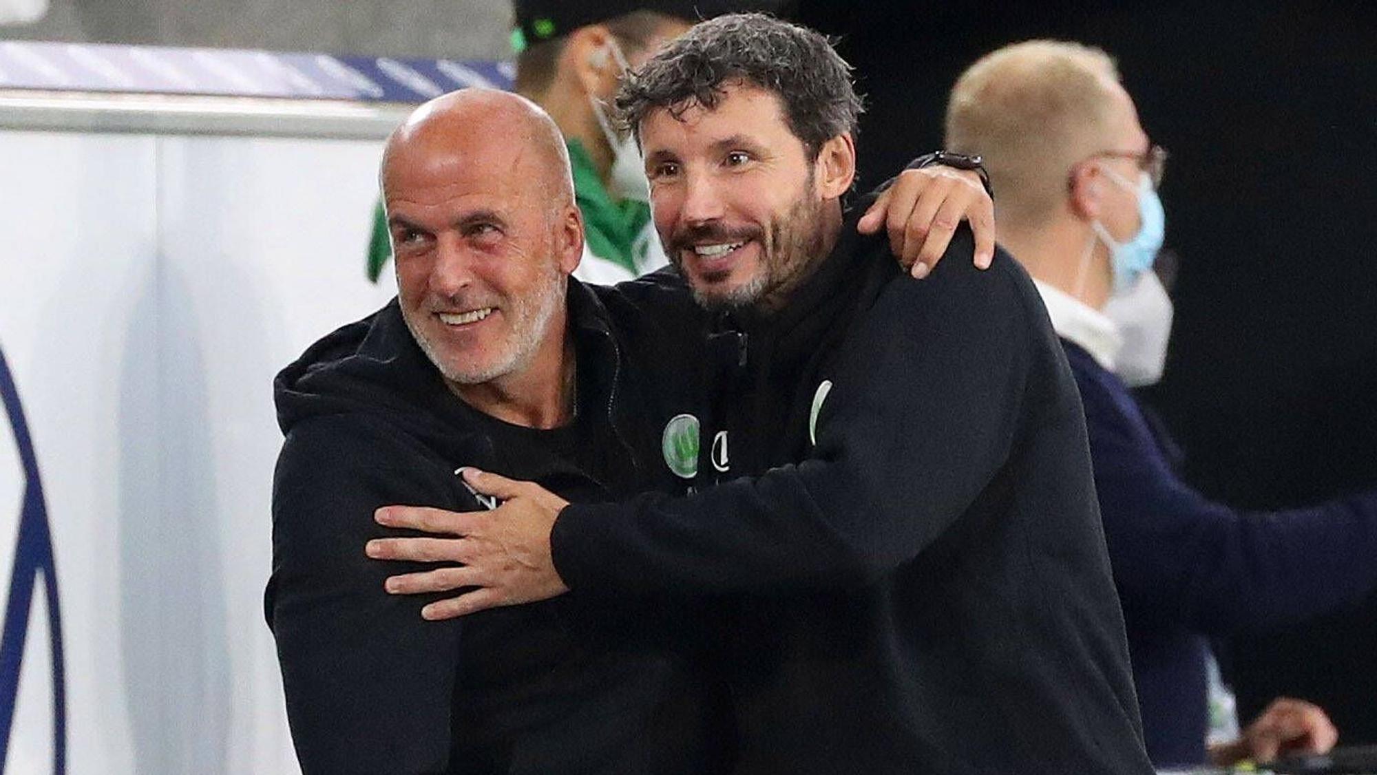Mark van Bommel (r.) ist am Sonntag (24. Oktober 2021) als Cheftrainer bei Bundesligist VfL Wolfsburg entlassen worden. Muss nun auch sein Assistent Michael Frontzeck, ehemaliger Gladbach-Coach, um seinen Job bangen? Frontzeck und van Bommel umarmen sich. Dieses Foto stammt vom 29. August 2021.