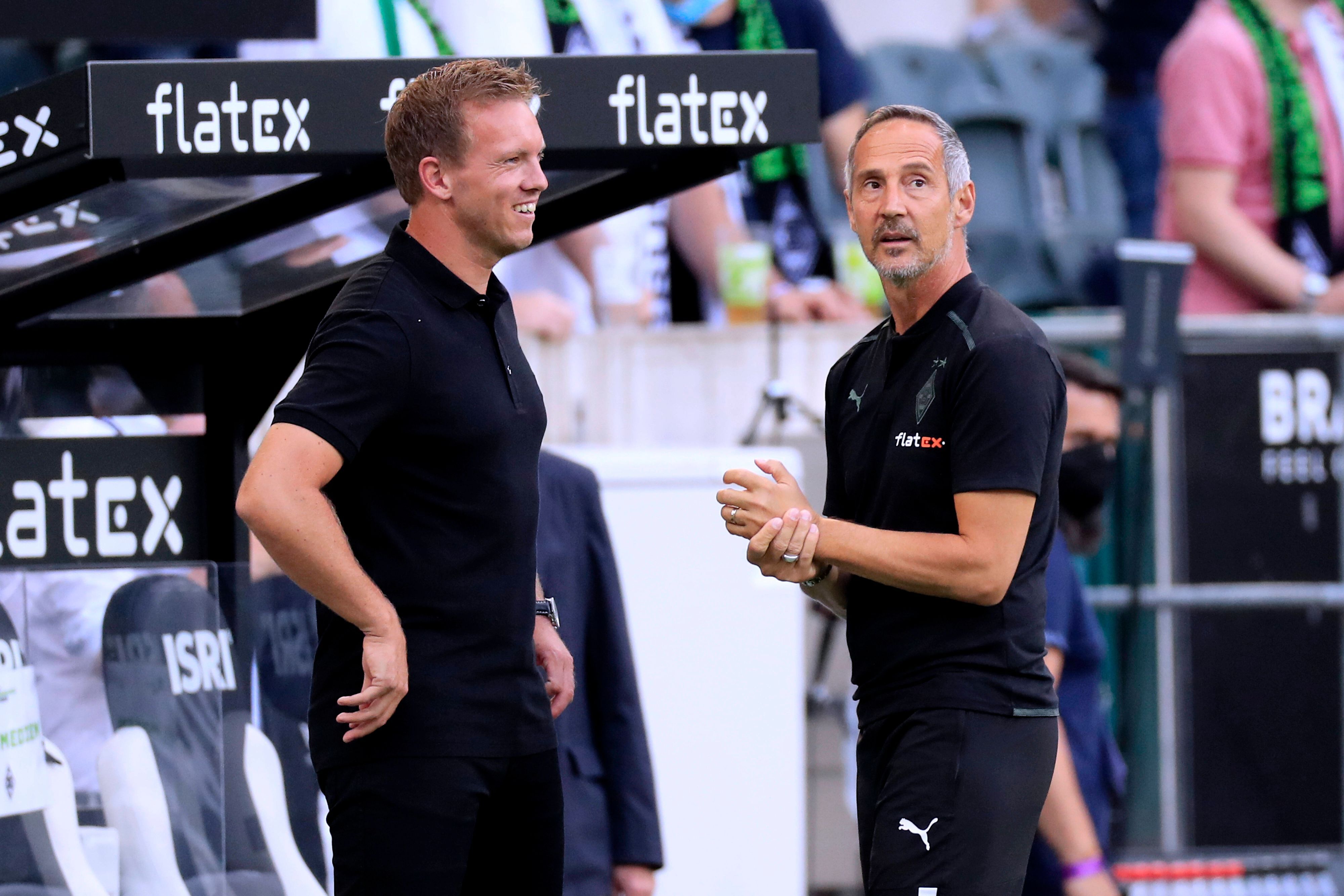 Adi Hütter (r.), Trainer von Fußball-Bundesligist Borussia Mönchengladbach, am 13. August 2021 im Borussia-Park im Gespräch mit seinem Kollegen Julian Nagelsmann (l.), der bei Bayern München unter Vertrag steht. Nagelsmann lächelt.