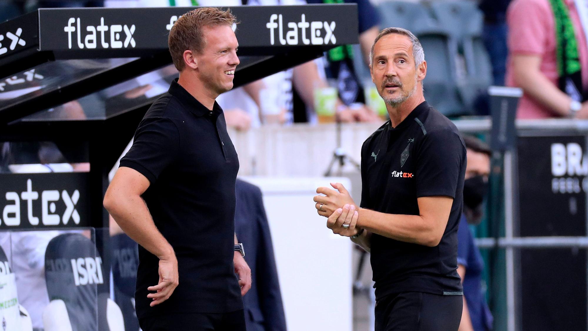 Adi Hütter (r.), Trainer von Fußball-Bundesligist Borussia Mönchengladbach, am 13. August 2021 im Borussia-Park im Gespräch mit seinem Kollegen Julian Nagelsmann (l.), der bei Bayern München unter Vertrag steht. Nagelsmann lächelt.