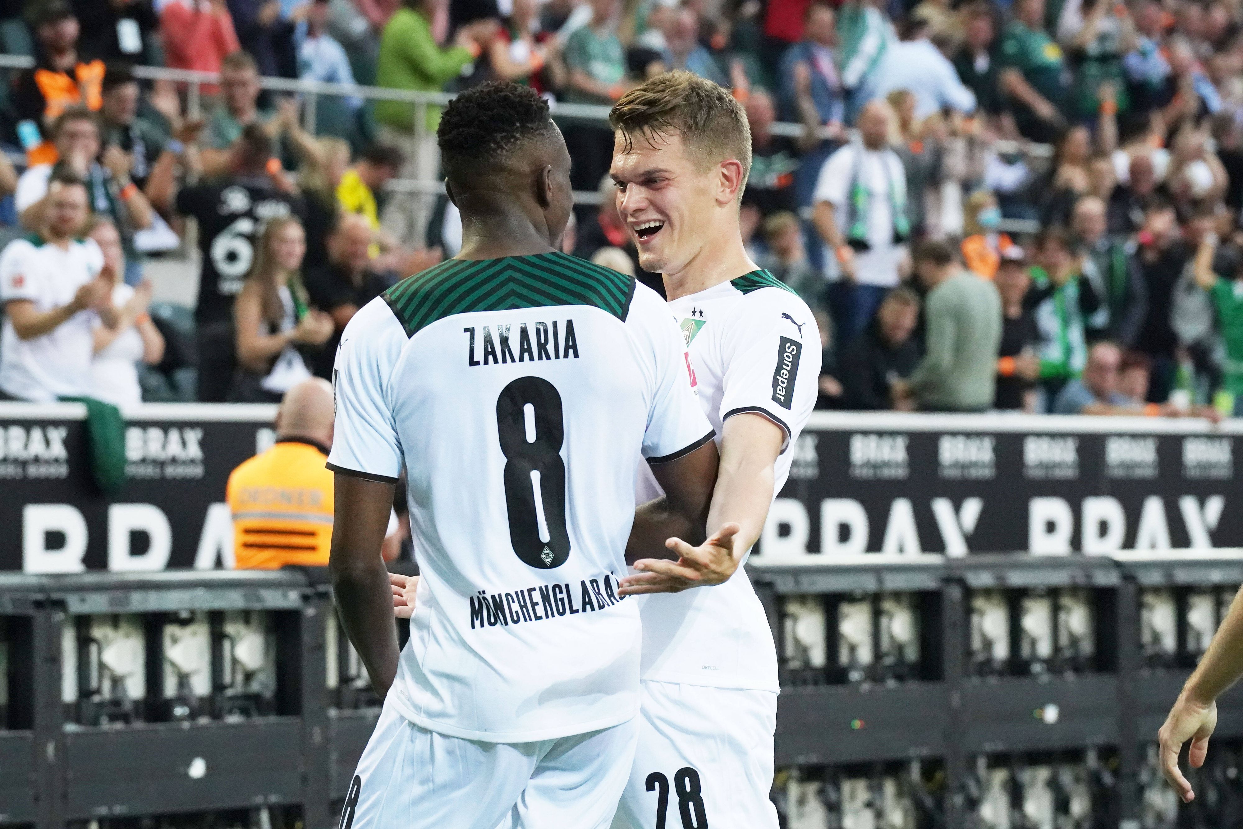 Denis Zakaria (l.) und Matthias Ginter (r.), beide noch bis Ende Juni 2022 bei Fußball-Bundesligist Borussia Mönchengladbach unter Vertrag, freuen sich gemeinsam über den Siegtreffer im Duell gegen Dortmund am 25. September 2021. Beide schauen sich an und lachen.