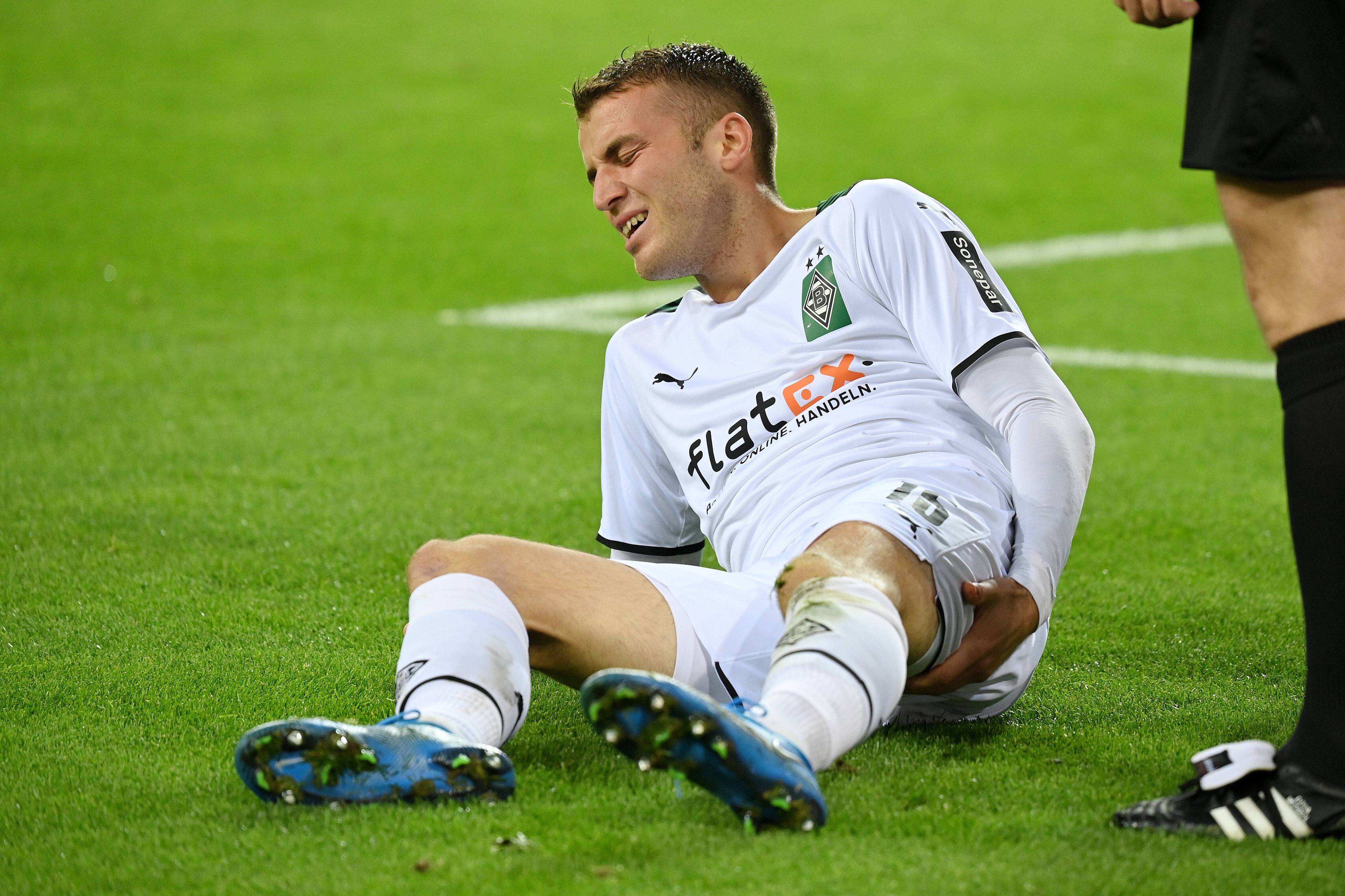 Jordan Beyer von Borussia Mönchengladbach, hier am 27. Oktober 2021, liegt auf dem Boden und hält sich den hinteren Oberschenkel mit schmerzverzerrtem Gesicht.
