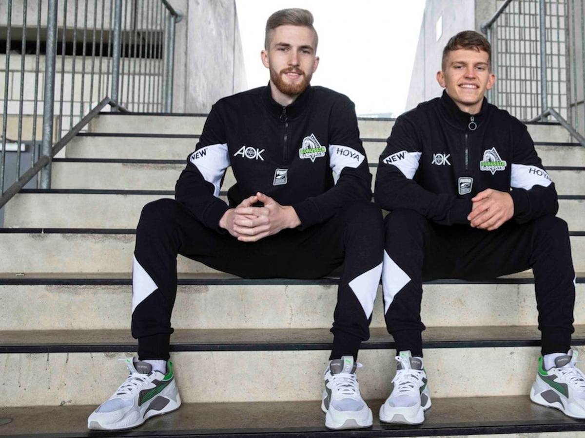 Borussias E-Sportler Yannick Reiners (l.) und Eleftherios „Lefti“ Ilias (r.), sitzen nebeneinander auf den Stufen im Borussia-Park und peilen die Meisterschaft an.
