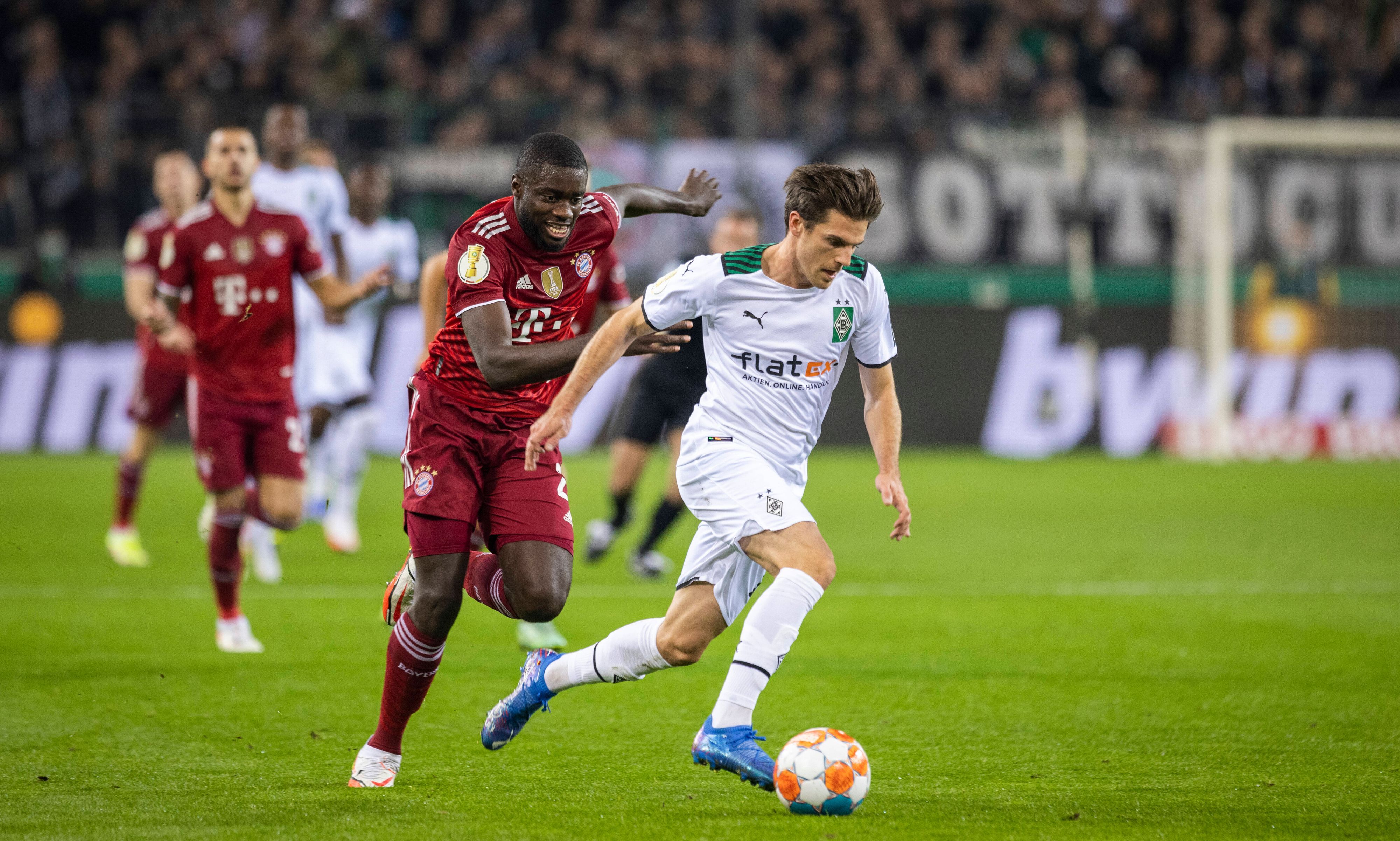 Verteidiger Dayot Upamecano (l.) von Bayern München läuft Offensivspieler Jonas Hofmann (r.) von Borussia Mönchengladbach im DFB-Pokalspiel am 27. Oktober 2021 im Borussia-Park hinterher. Hofmann sprintet mit dem Ball am rechten Fuß dem Franzosen davon.