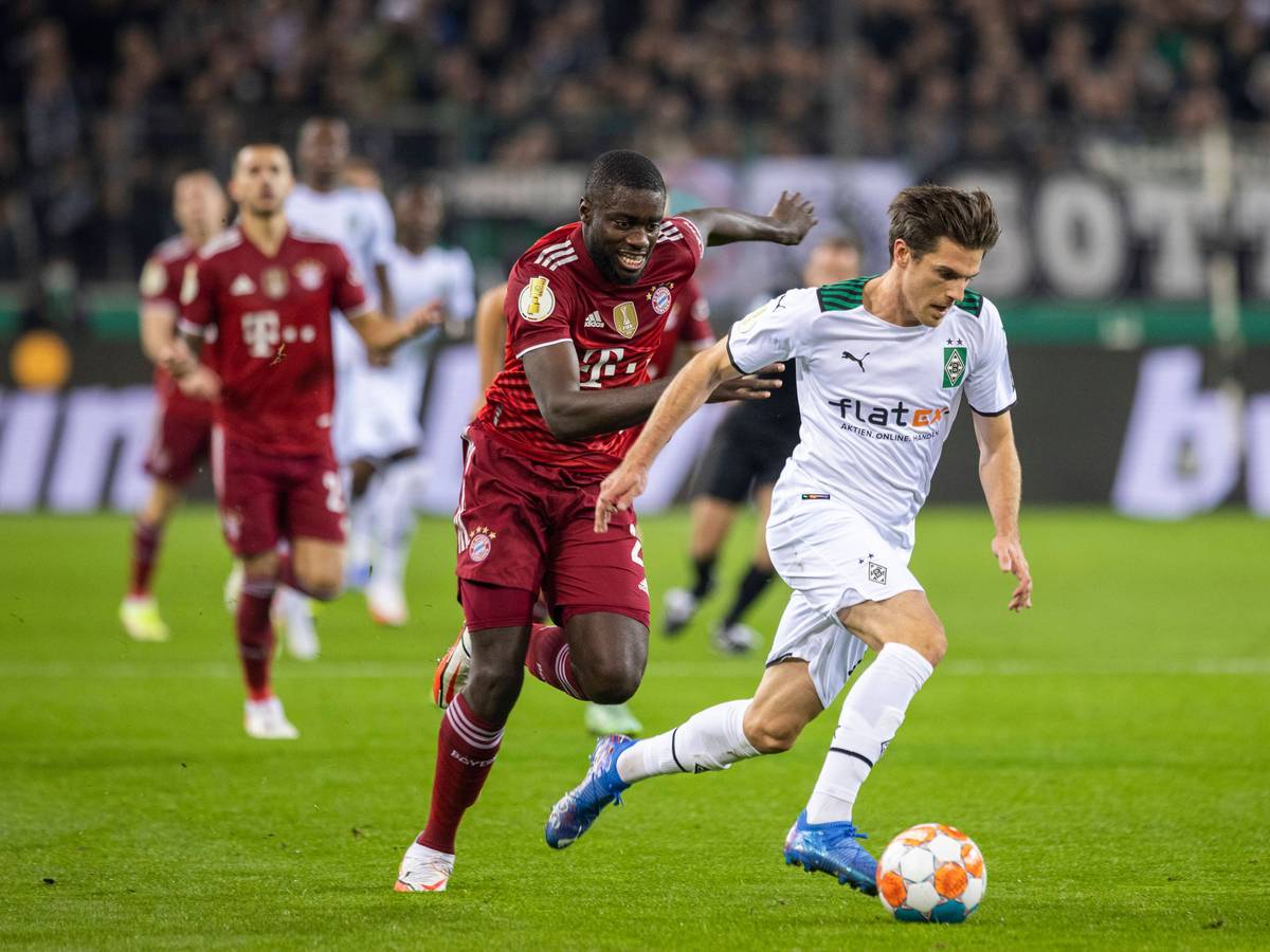 Verteidiger Dayot Upamecano (l.) von Bayern München läuft Offensivspieler Jonas Hofmann (r.) von Borussia Mönchengladbach im DFB-Pokalspiel am 27. Oktober 2021 im Borussia-Park hinterher. Hofmann sprintet mit dem Ball am rechten Fuß dem Franzosen davon.