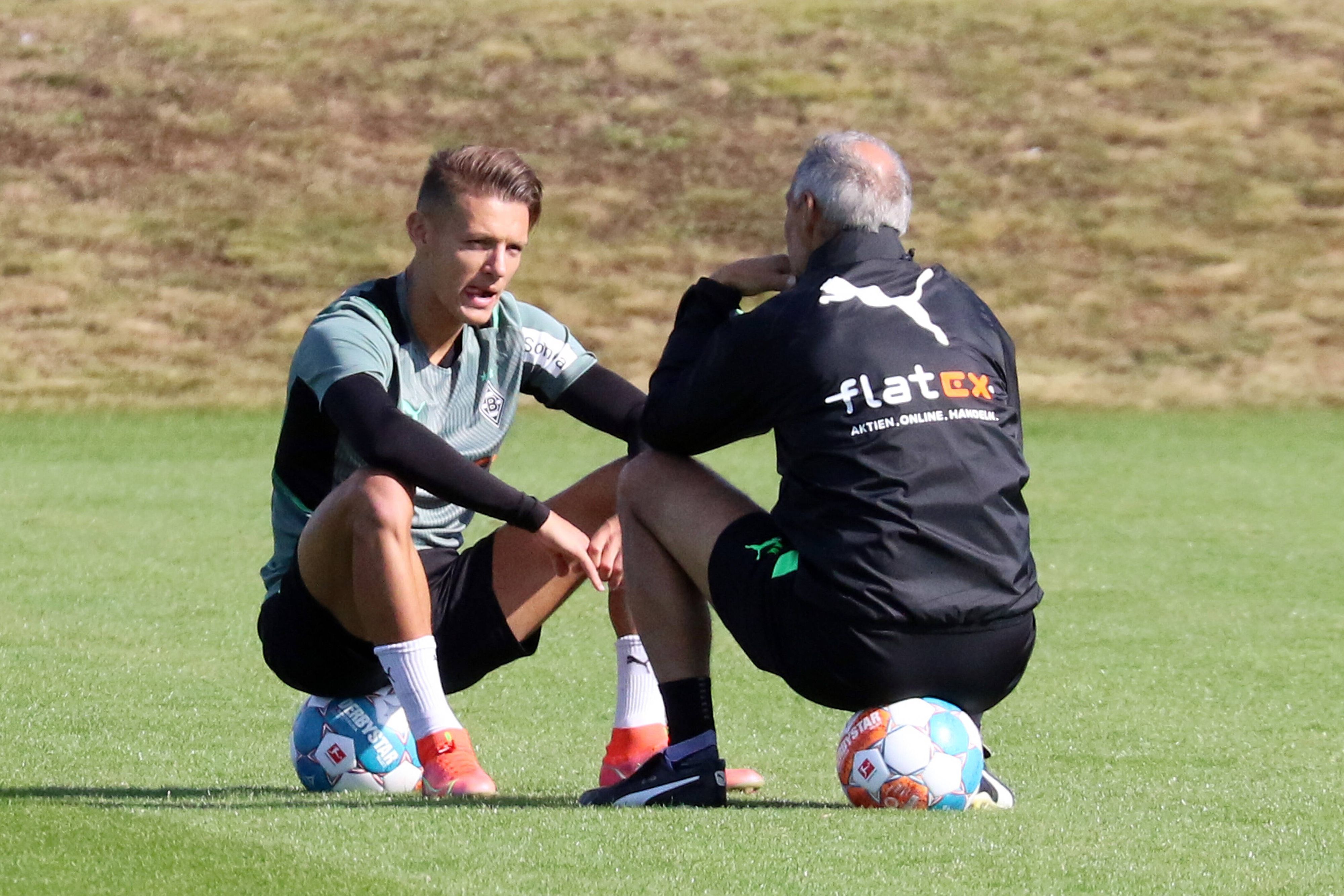Hannes Wolf (l.) im Gespräch mit Adi Hütter (r.) von Borussia Mönchengladbach, beide sitzen auf Fußbällen auf dem Trainingsgelände am 23. September 2021.