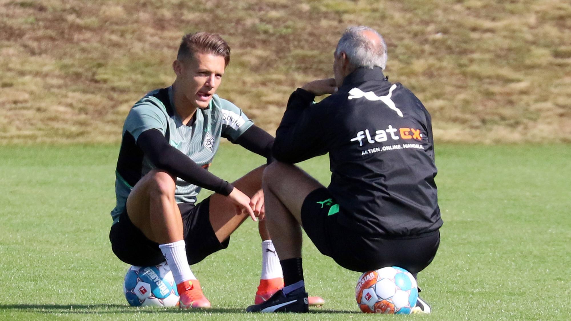 Hannes Wolf (l.) im Gespräch mit Adi Hütter (r.) von Borussia Mönchengladbach, beide sitzen auf Fußbällen auf dem Trainingsgelände am 23. September 2021.